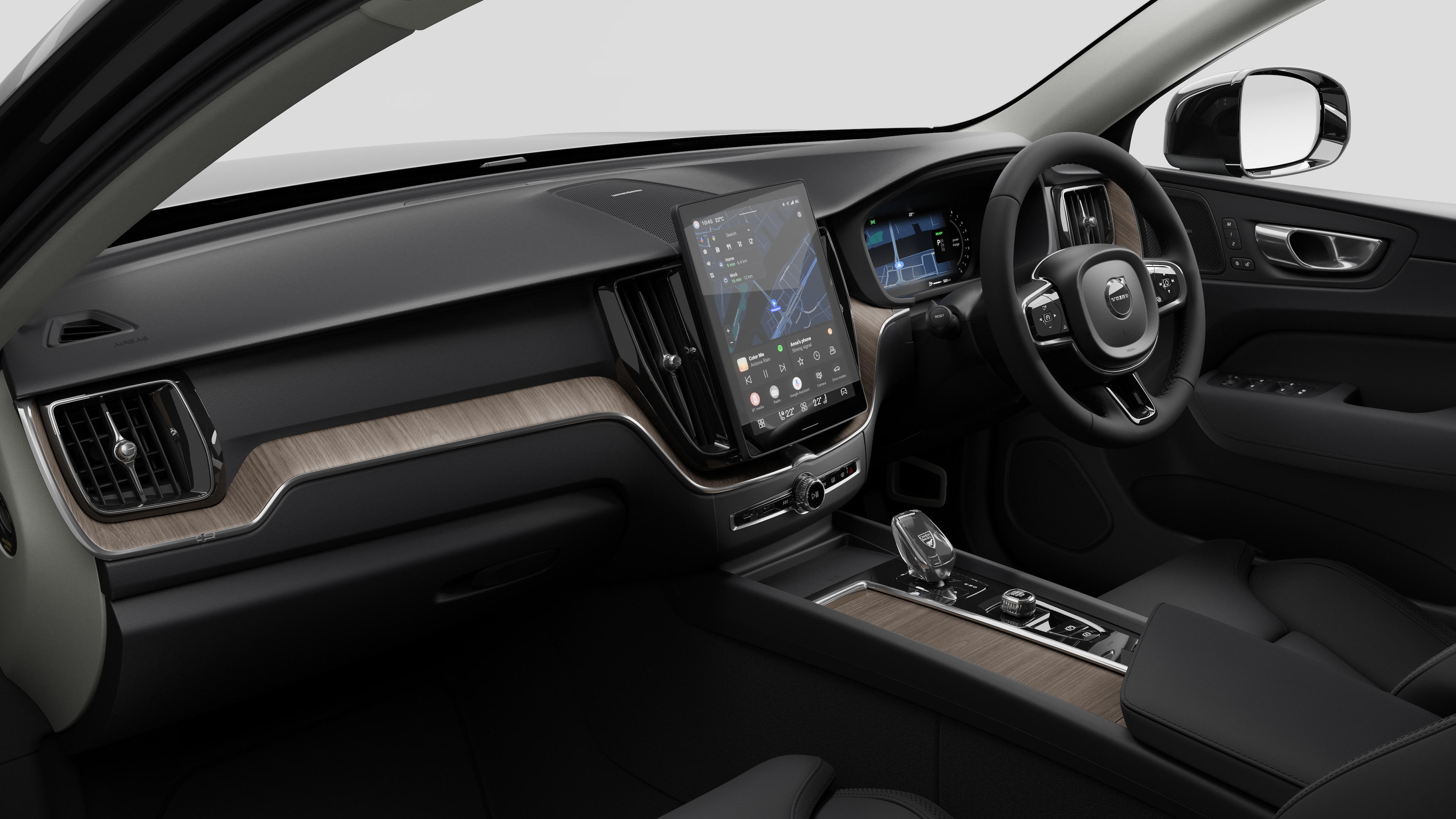 Interior view of a Volvo car showing the dashboard, steering wheel, center console, and digital display screen in a plain studio background.