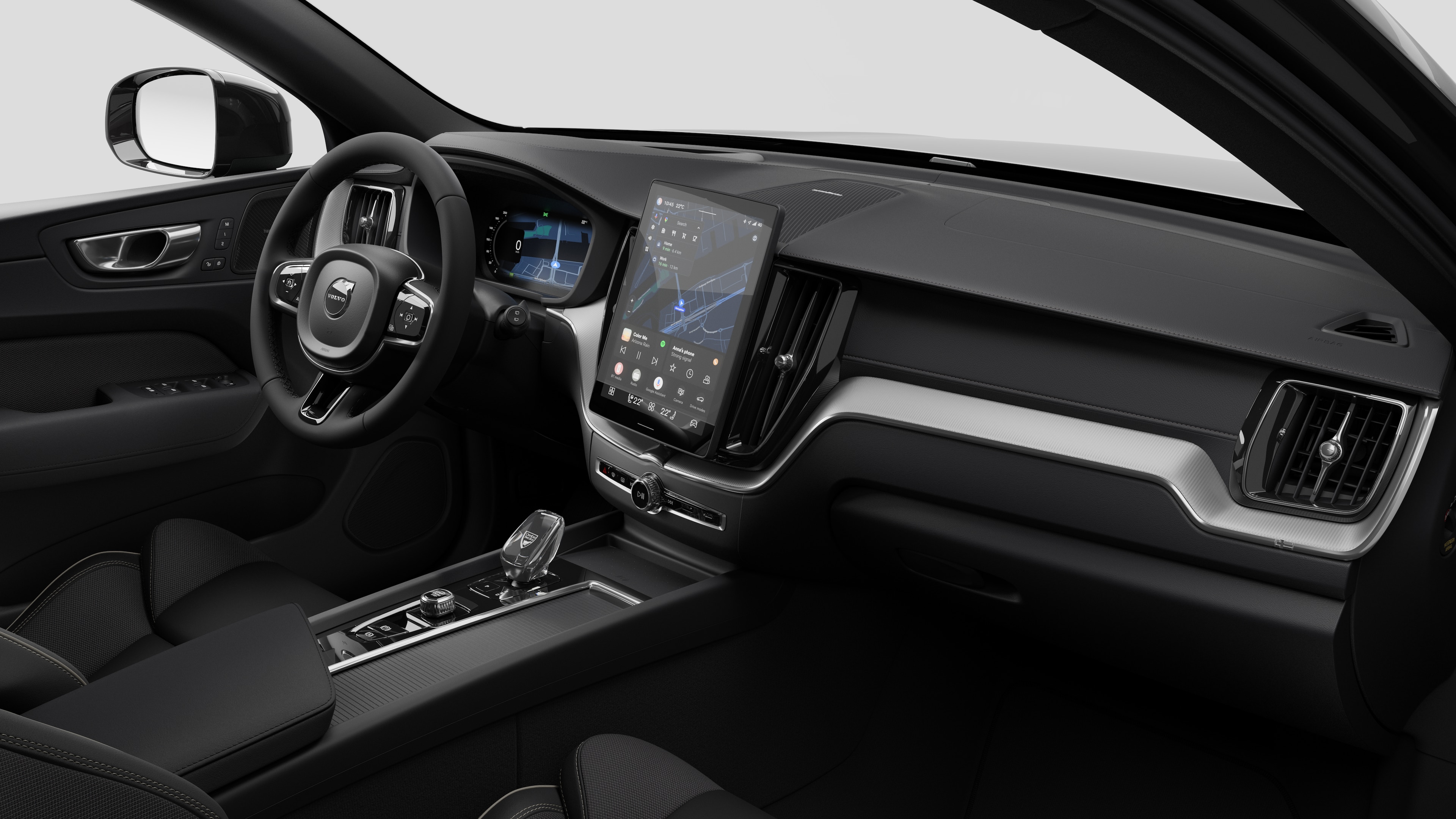 Interior view of a Volvo car showing the dashboard, steering wheel, center console, and digital display screen in a plain studio background.
