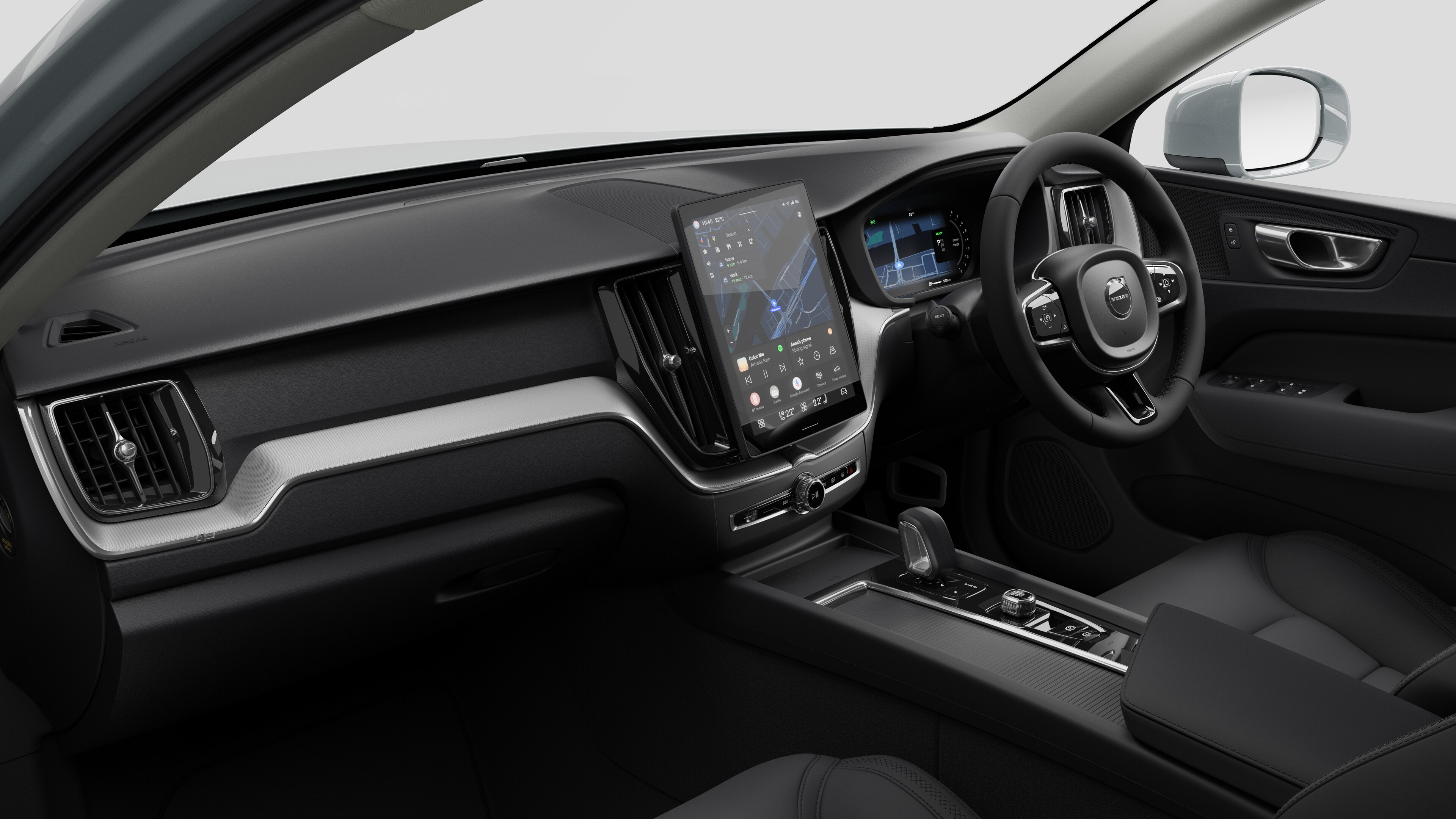 Interior view of a Volvo car showing the dashboard, steering wheel, center console, and digital display screen in a plain studio background.
