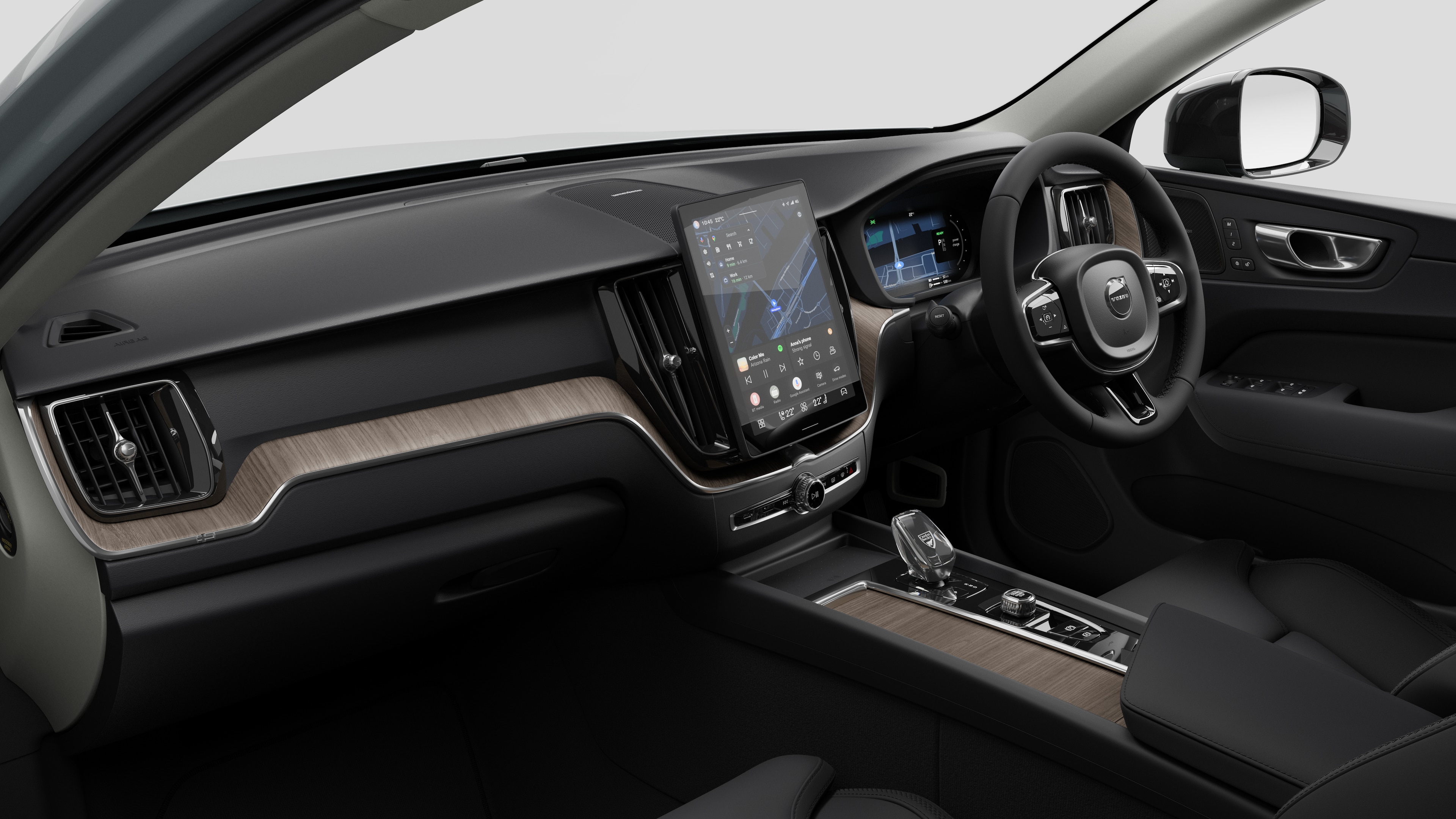 Interior view of a Volvo car showing the dashboard, steering wheel, center console, and digital display screen in a plain studio background.