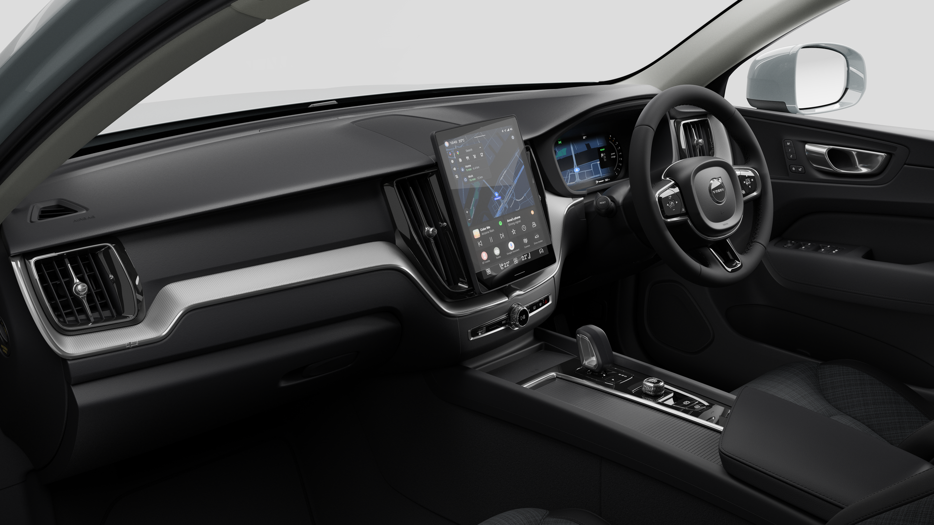 Interior view of a Volvo car showing the dashboard, steering wheel, center console, and digital display screen in a plain studio background.