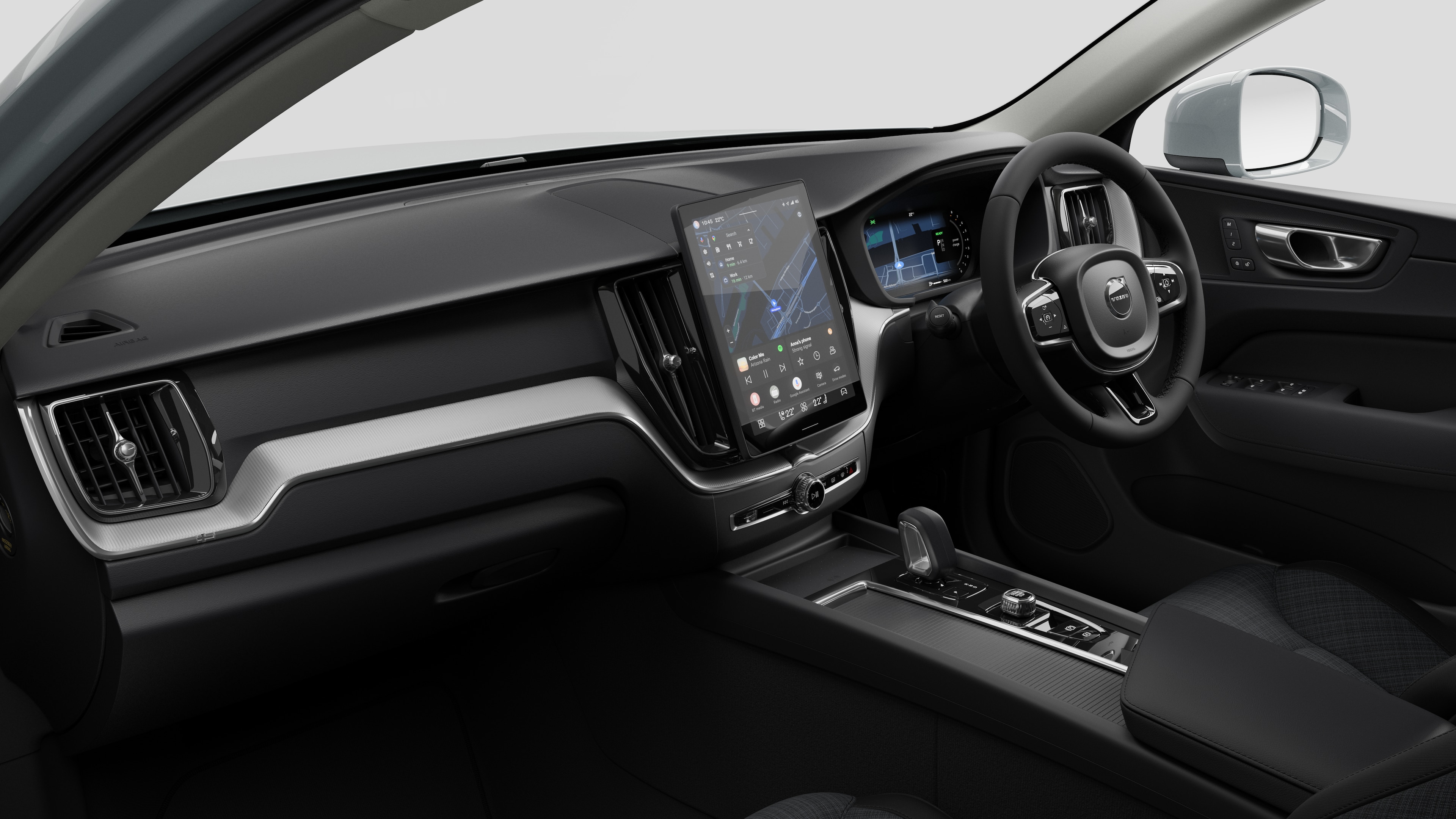 Interior view of a Volvo car showing the dashboard, steering wheel, center console, and digital display screen in a plain studio background.