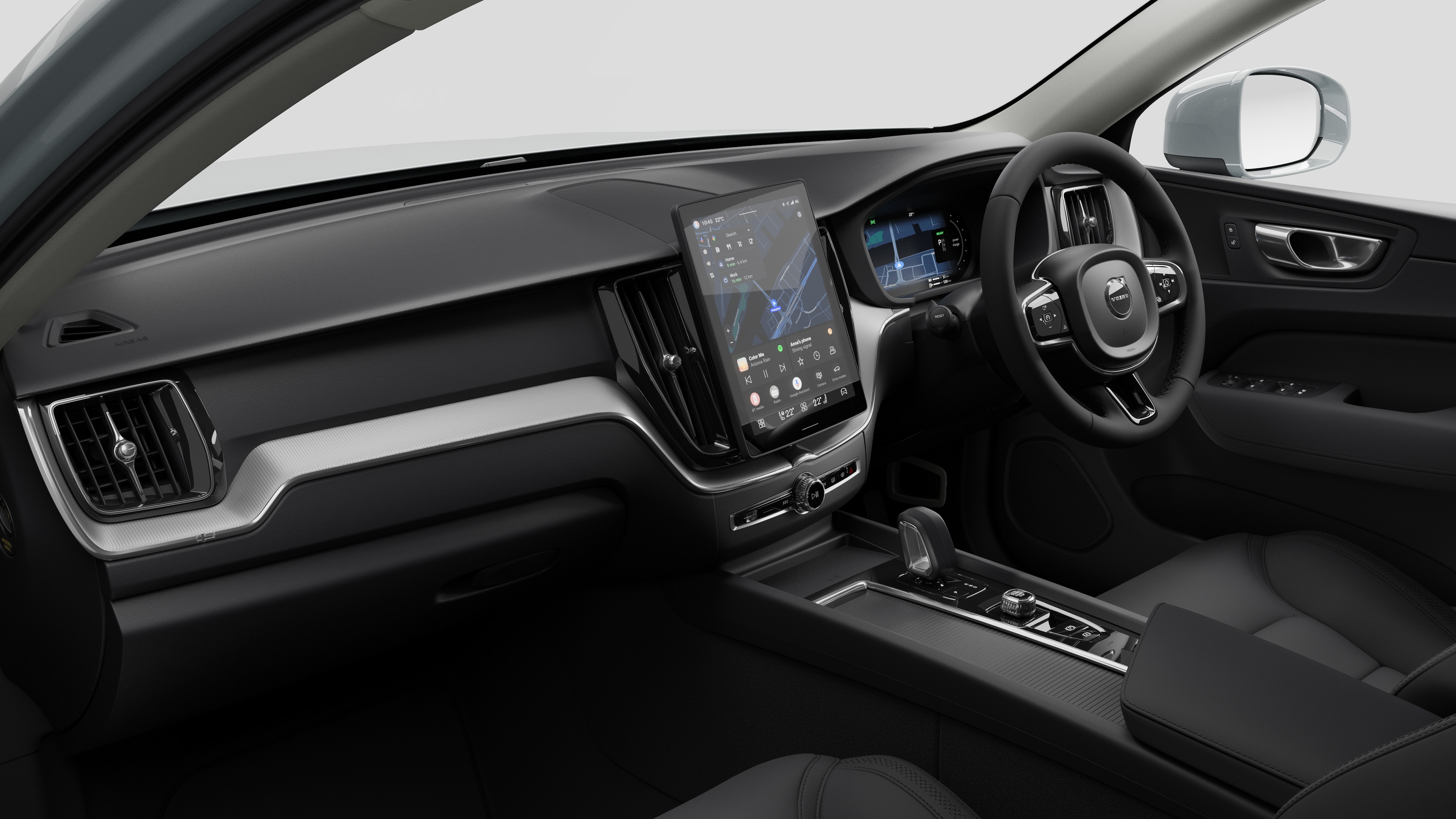 Interior view of a Volvo car showing the dashboard, steering wheel, center console, and digital display screen in a plain studio background.