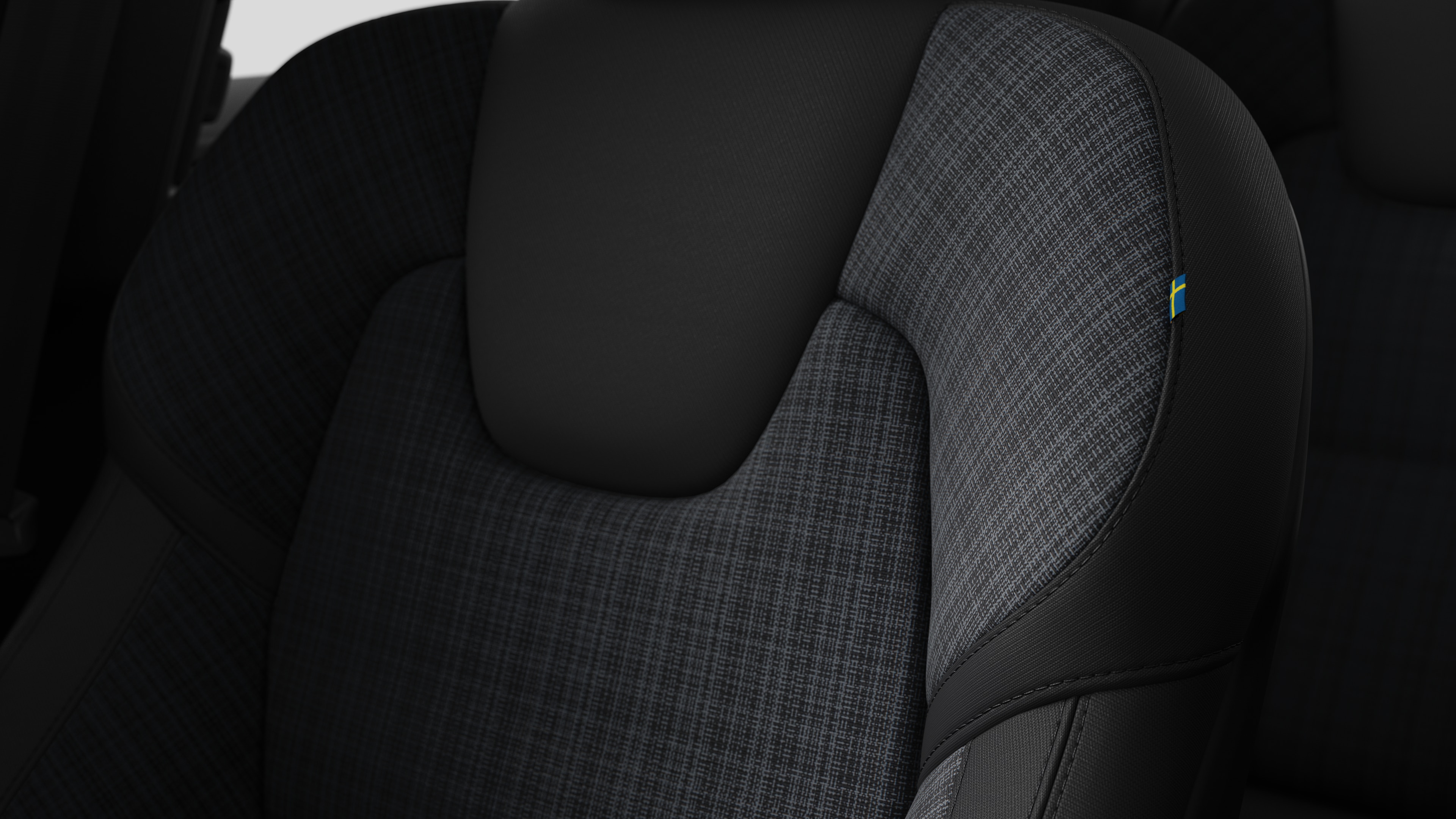 Close-up of Volvo car interior seat detail showing stitching and a small Swedish flag tag.