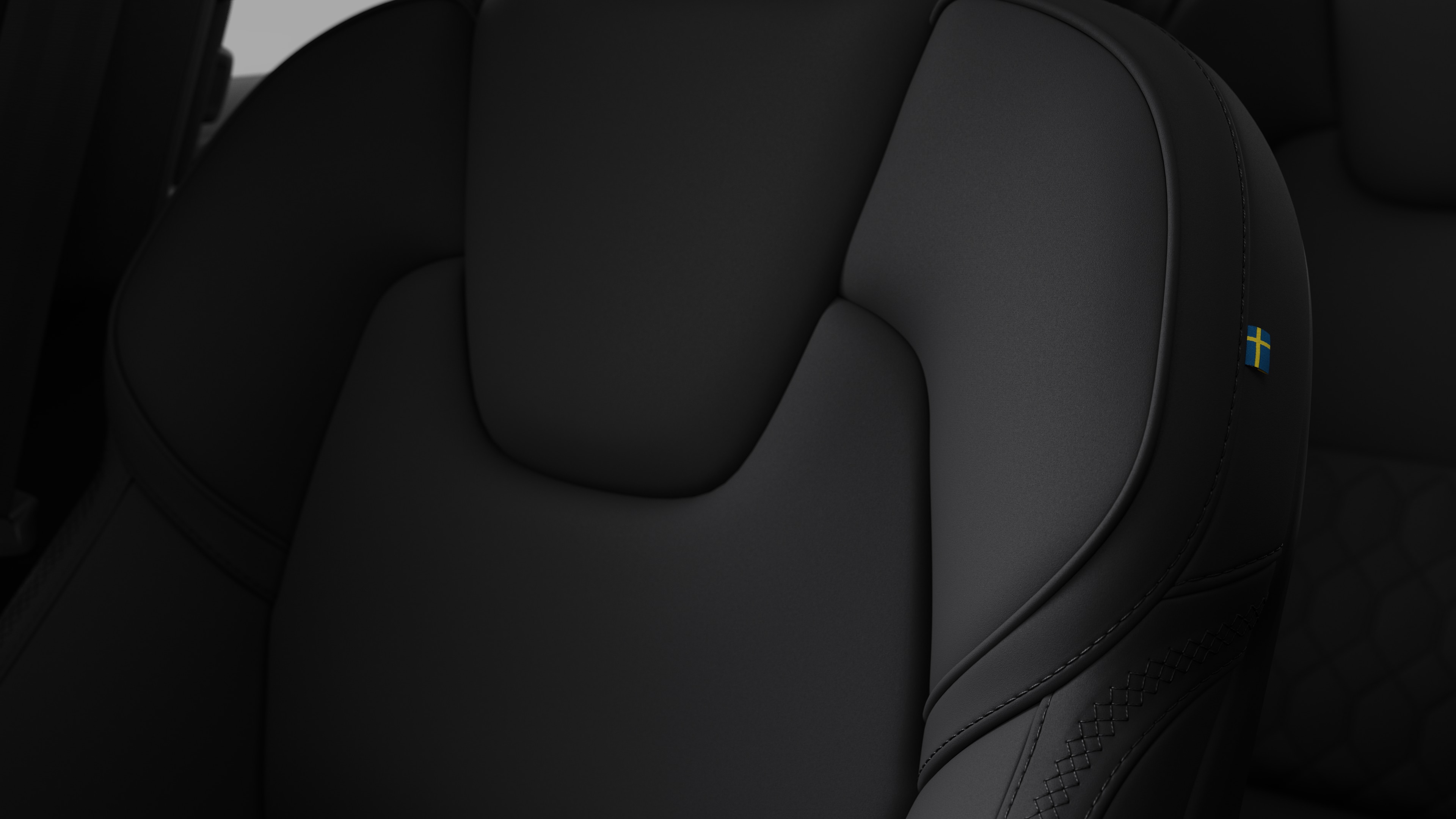 Close-up of Volvo car interior seat detail showing stitching and a small Swedish flag tag.