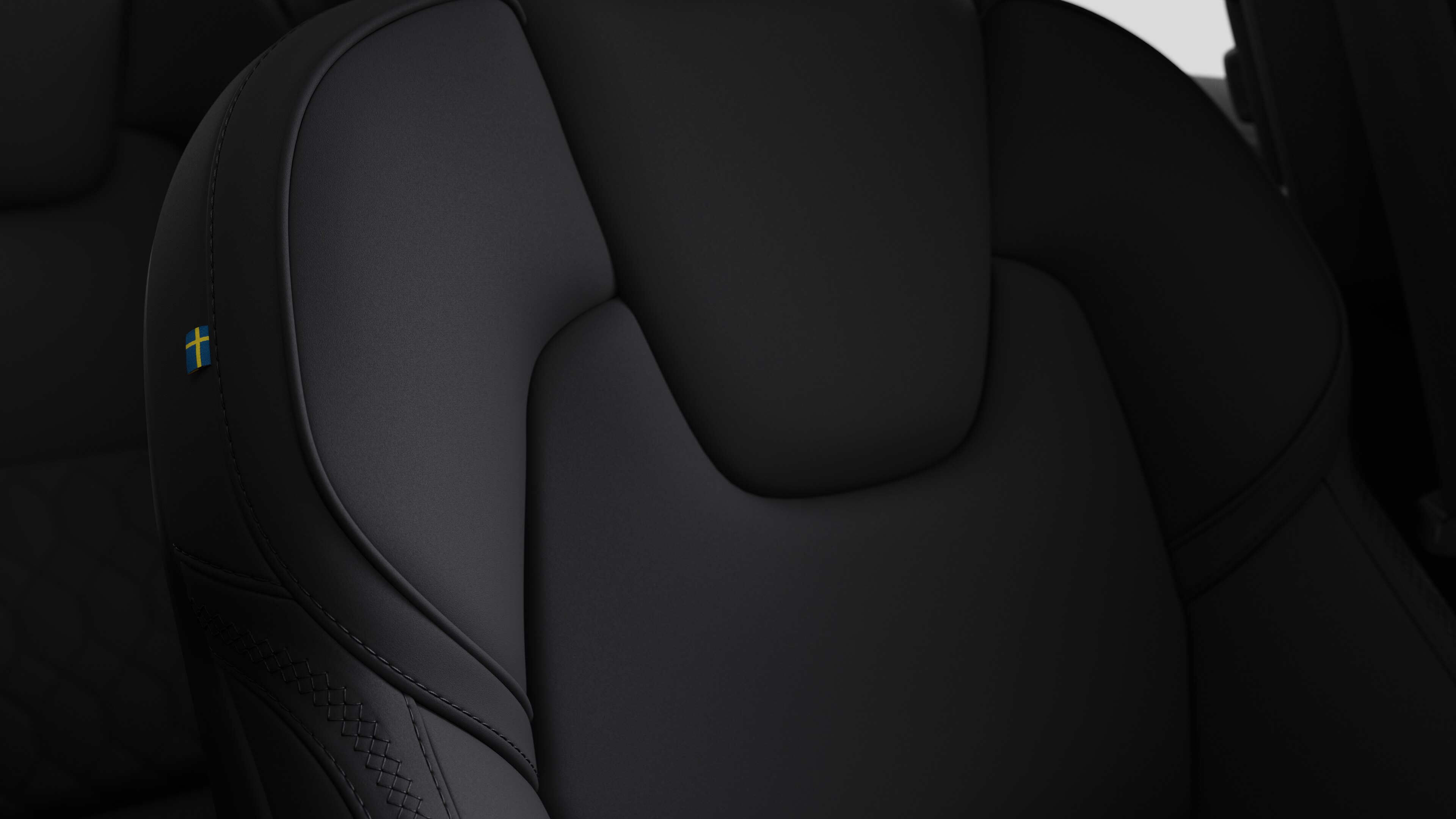 Close-up of Volvo car interior seat detail showing stitching and a small Swedish flag tag.