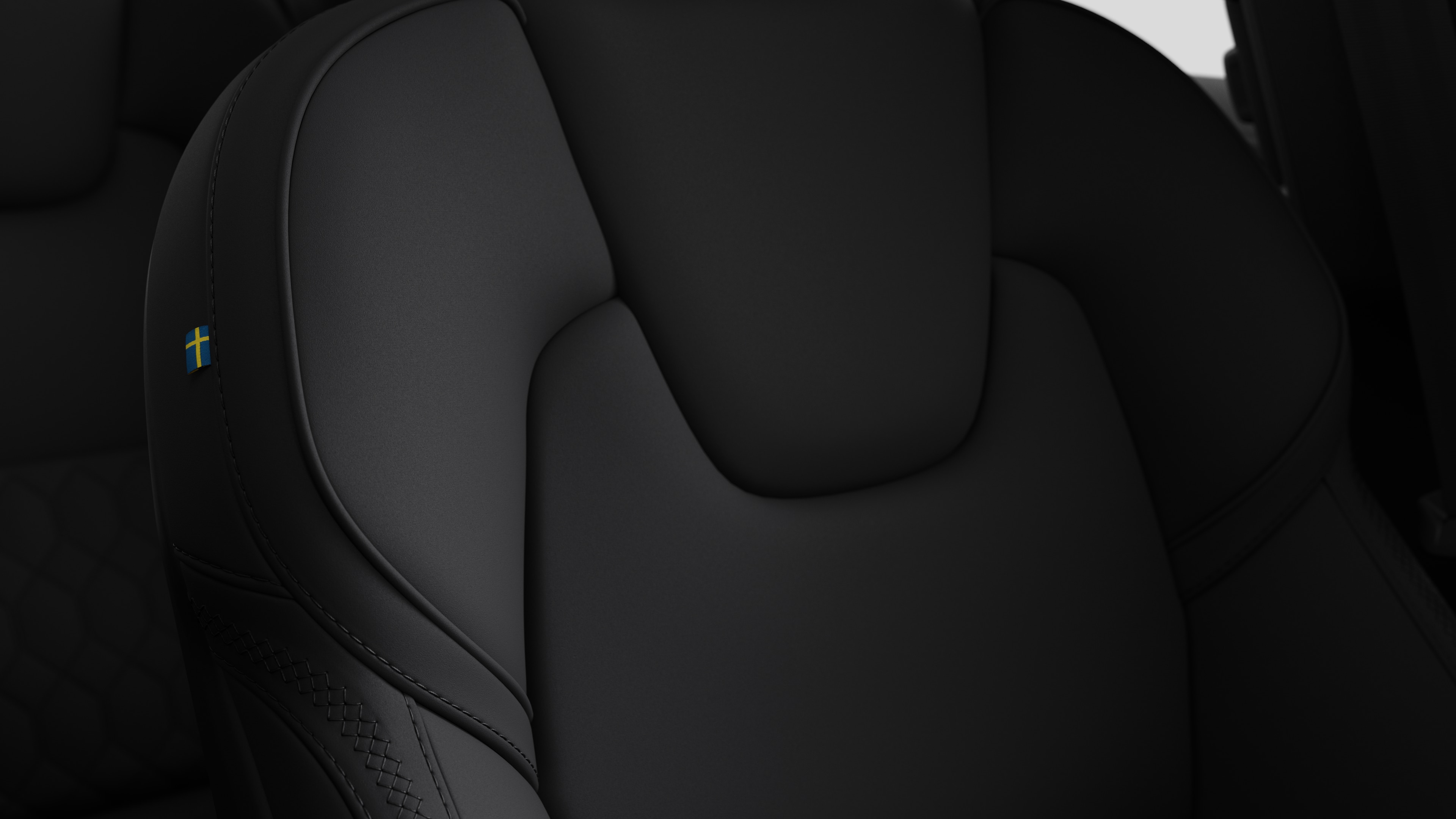 Close-up of Volvo car interior seat detail showing stitching and a small Swedish flag tag.