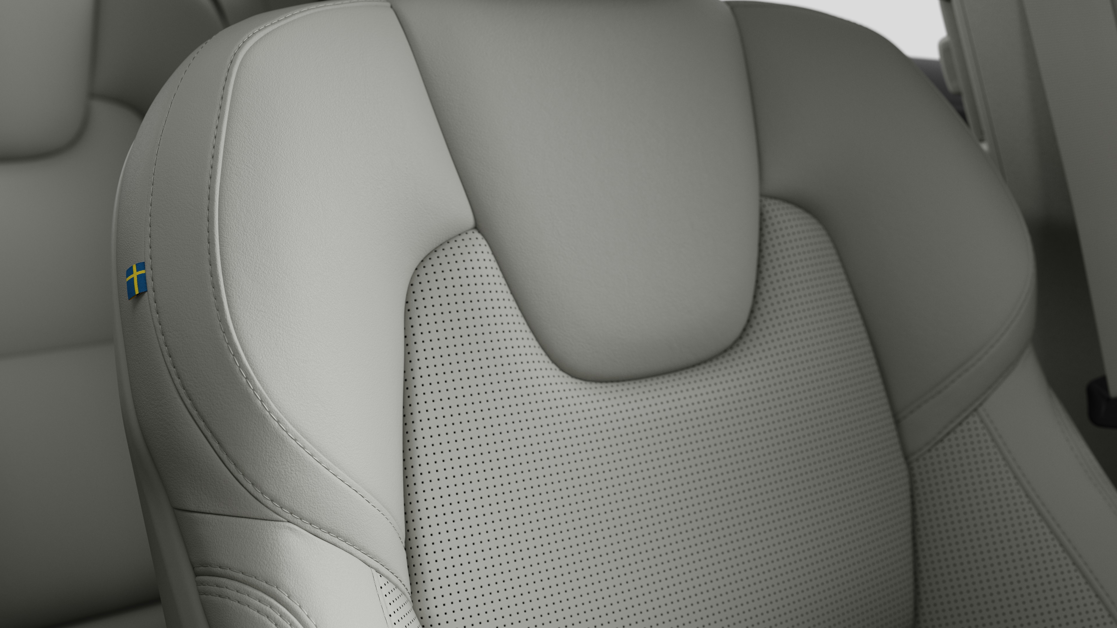 Close-up of Volvo car interior seat detail showing stitching and a small Swedish flag tag.