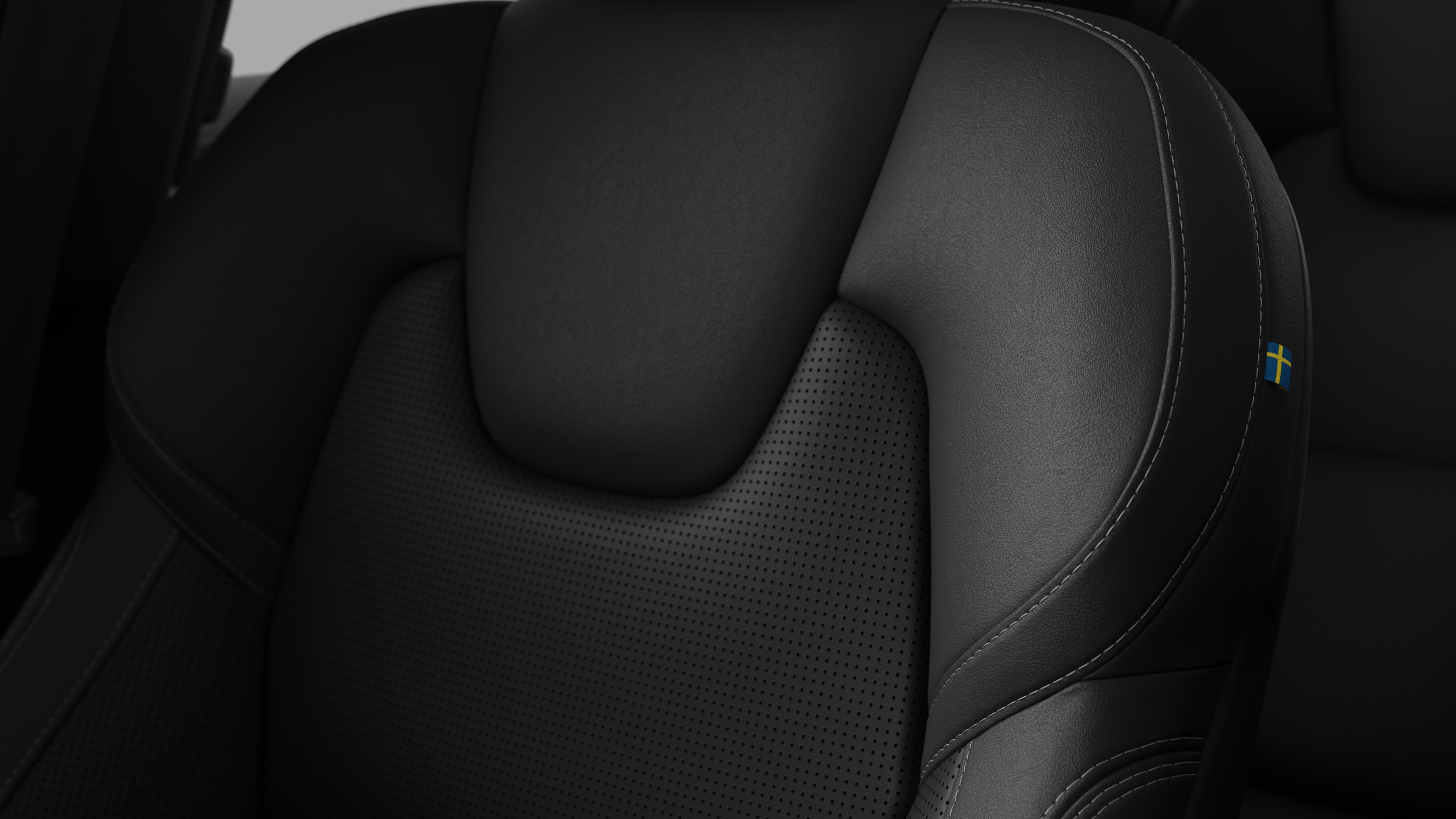 Close-up of Volvo car interior seat detail showing stitching and a small Swedish flag tag.