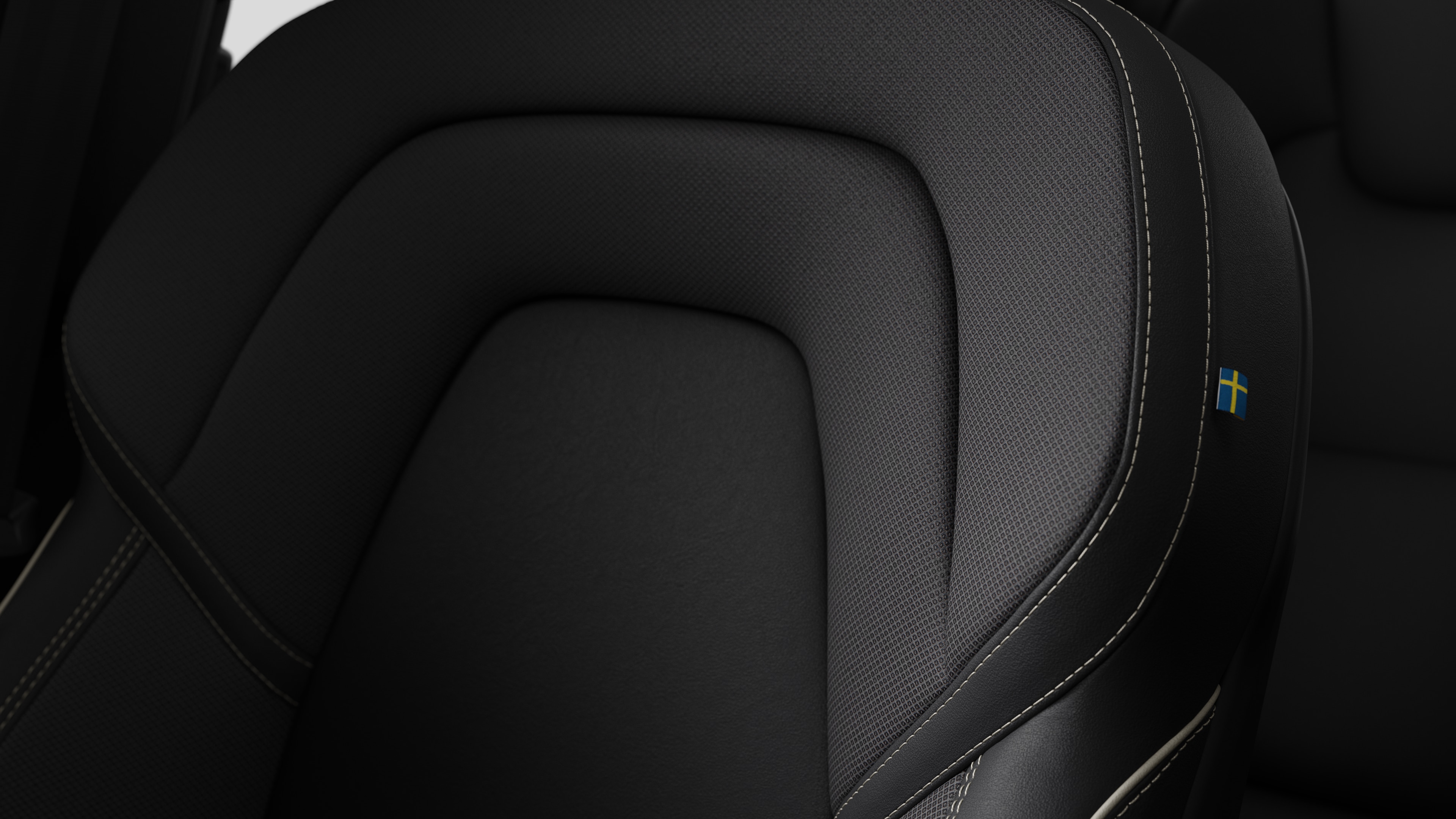 Close-up of Volvo car interior seat detail showing stitching and a small Swedish flag tag.