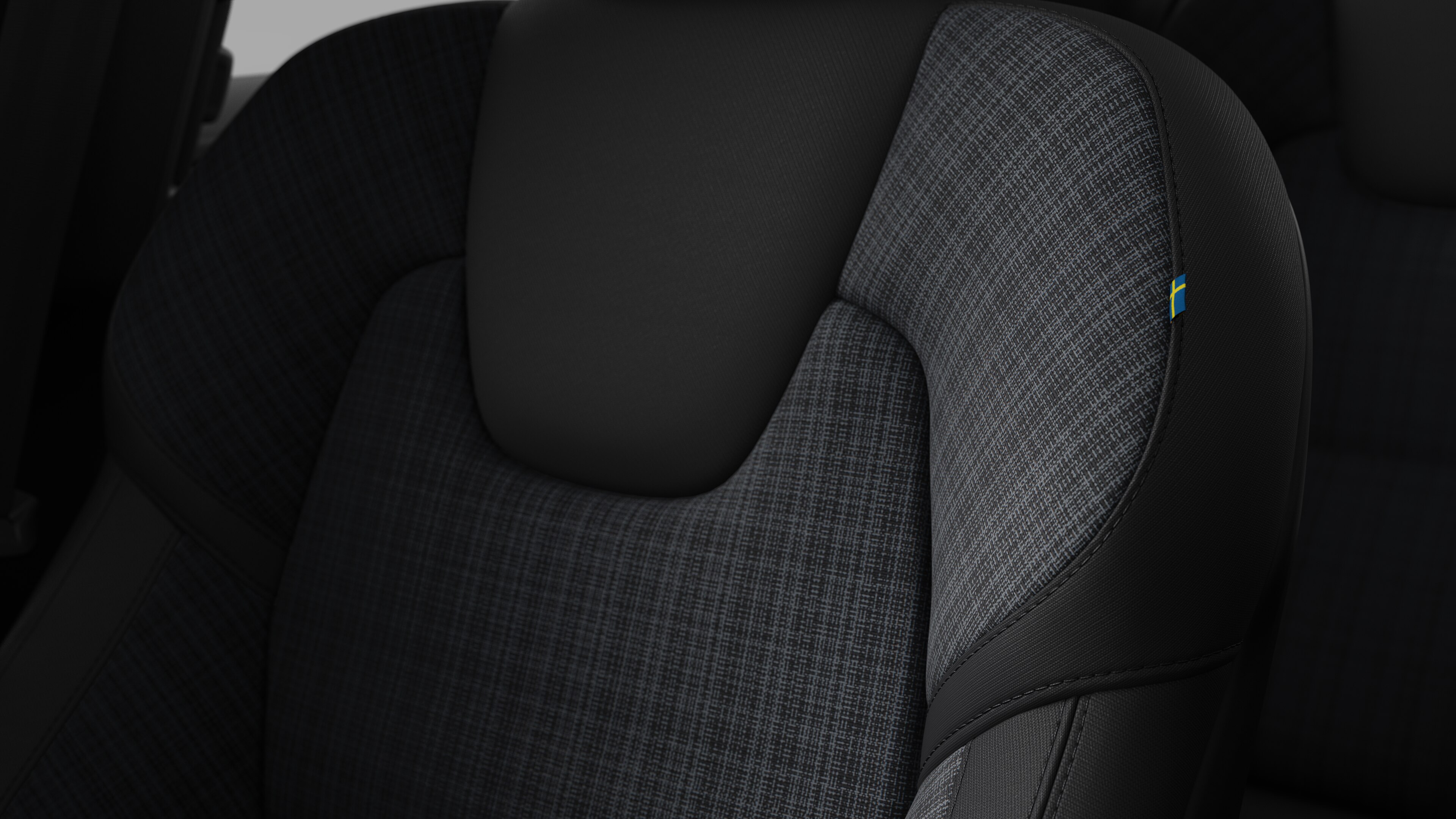 Primer plano del detalle del asiento interior del vehículo Volvo que muestra costuras y una pequeña etiqueta con la bandera sueca.