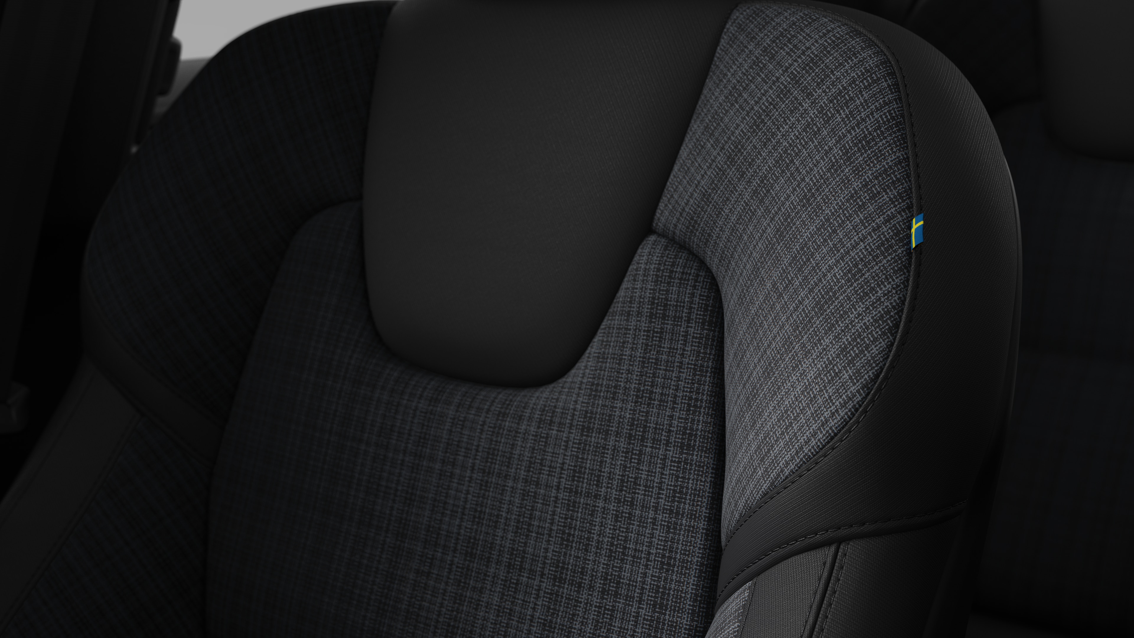 Primer plano del detalle del asiento interior del vehículo Volvo que muestra costuras y una pequeña etiqueta con la bandera sueca.