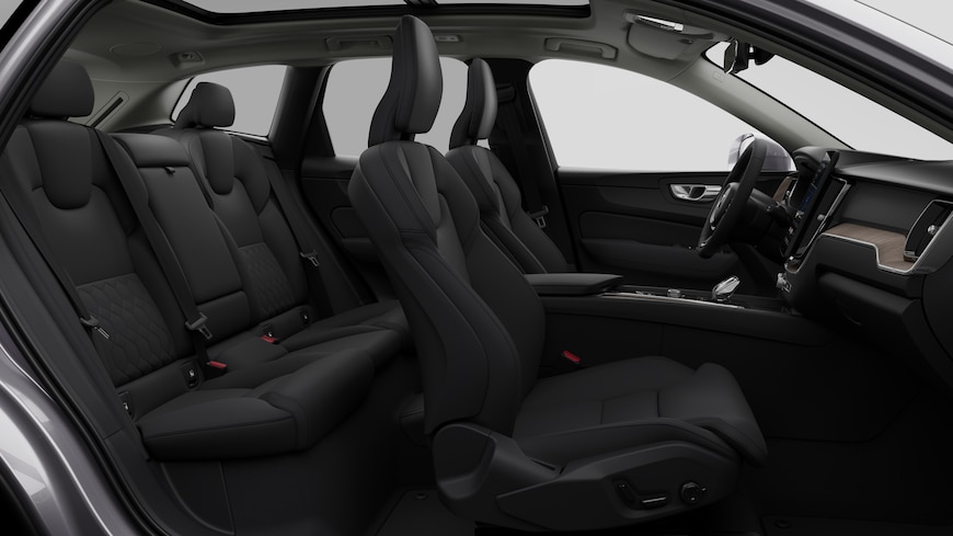 Vista lateral do interior do automóvel Volvo a mostrar os bancos dianteiros, os bancos do passageiro traseiro, o volante, o painel de instrumentos e a consola central, contra um fundo de estúdio simples.