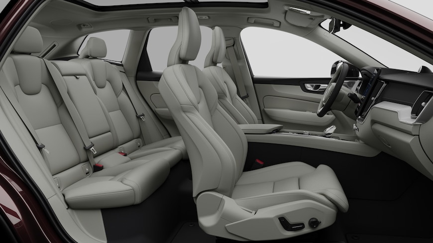 Volvo car interior side view showcasing front seats, rear passenger seats, steering wheel, dashboard, and center console, set against plain studio background.
