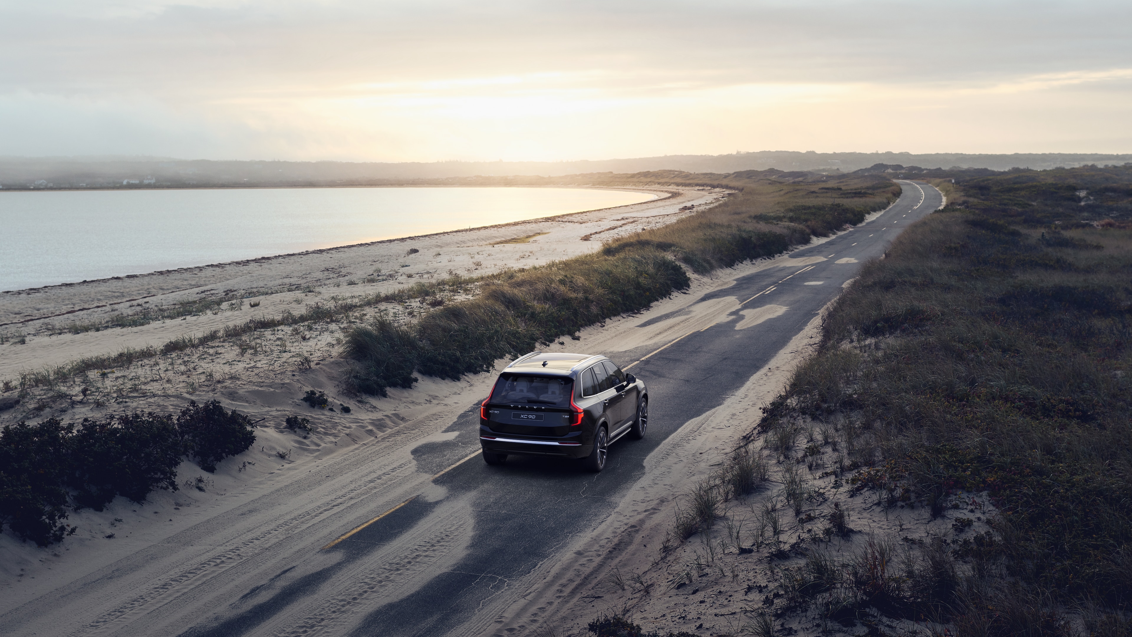 Vista trasera del vehículo Volvo en una sinuosa carretera costera con un fondo junto a la playa.