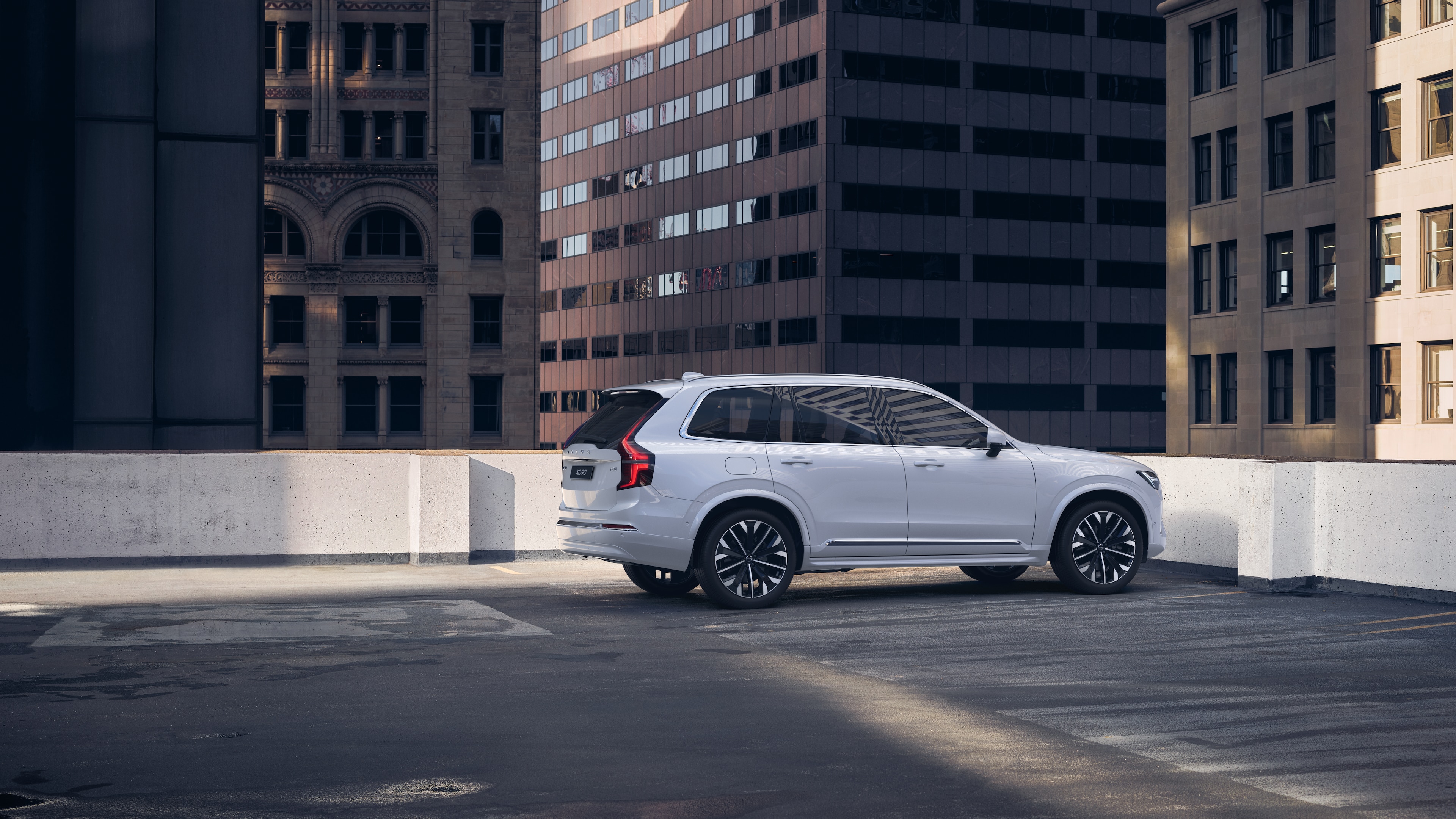 주변의 높은 건물들이 있는 도심 옥상 주차장에 있는 후면 3/4 뷰의 볼보 자동차.