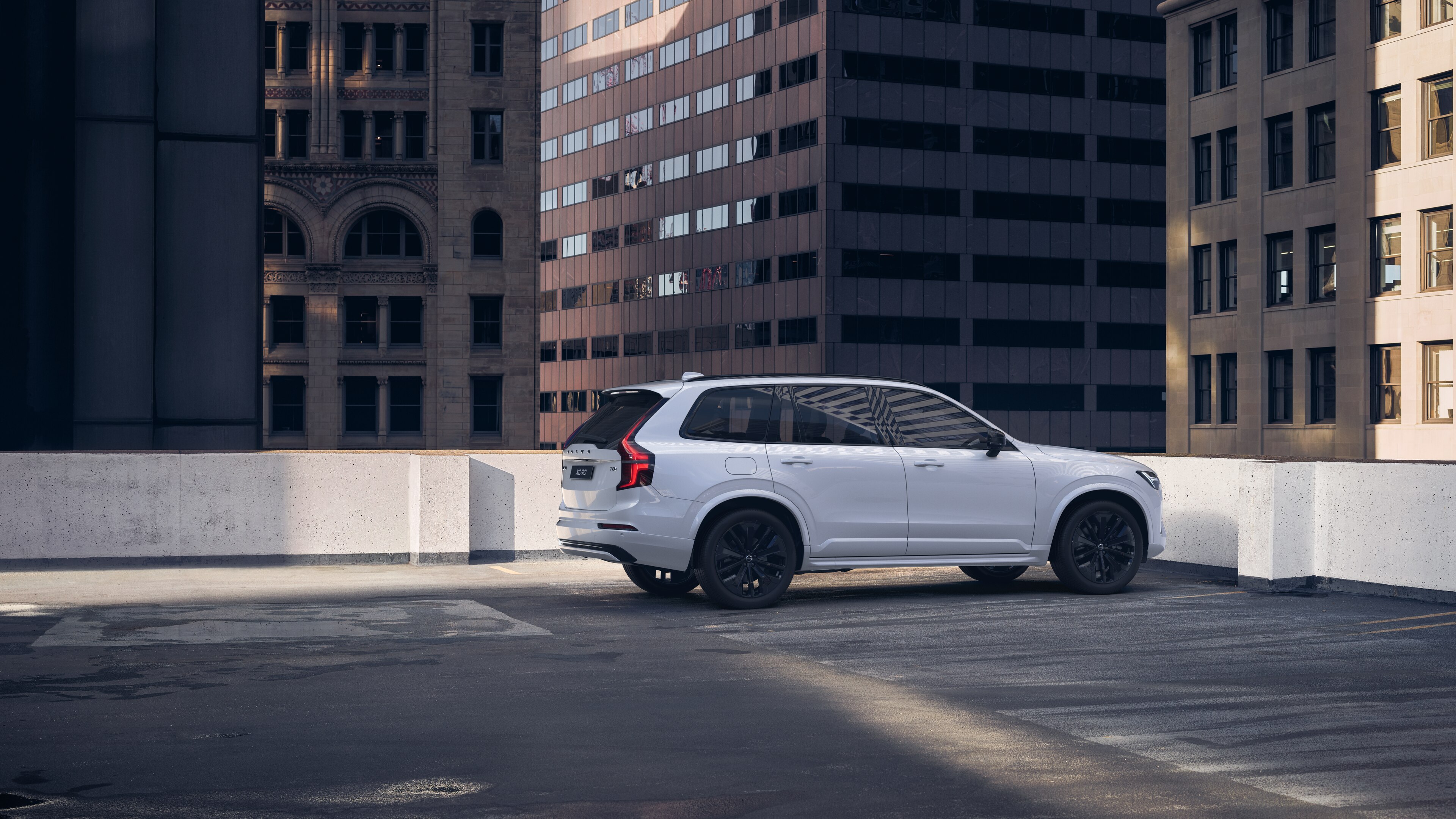 Widok samochodu Volvo z tyłu w trzech czwartych na miejskim parkingu na dachu wraz z otaczającymi go wysokimi budynkami