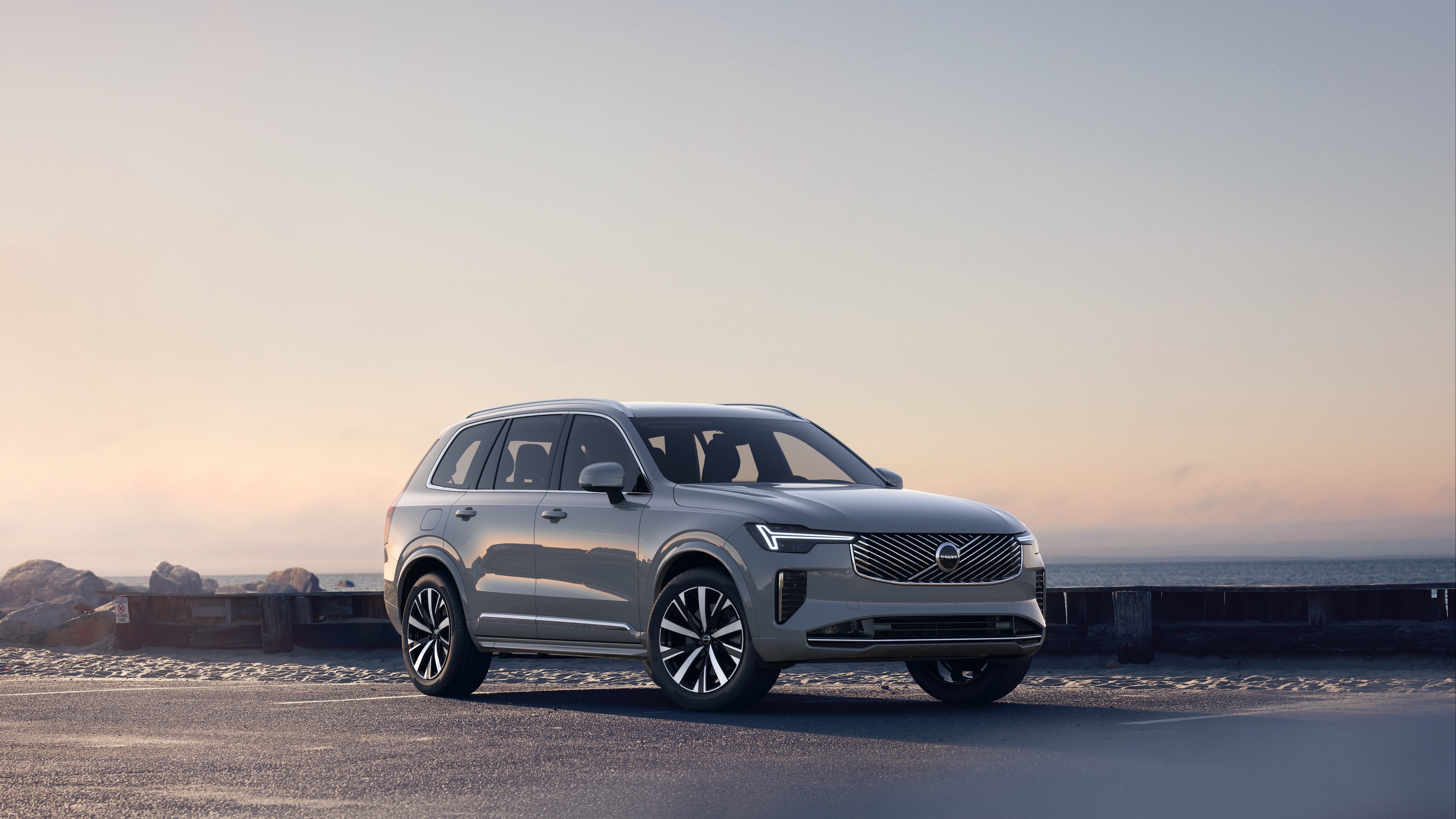 Volvo in driekwart aanzicht van kustweg, met de voor- en zijkant tegen een serene oceaanachtergrond.