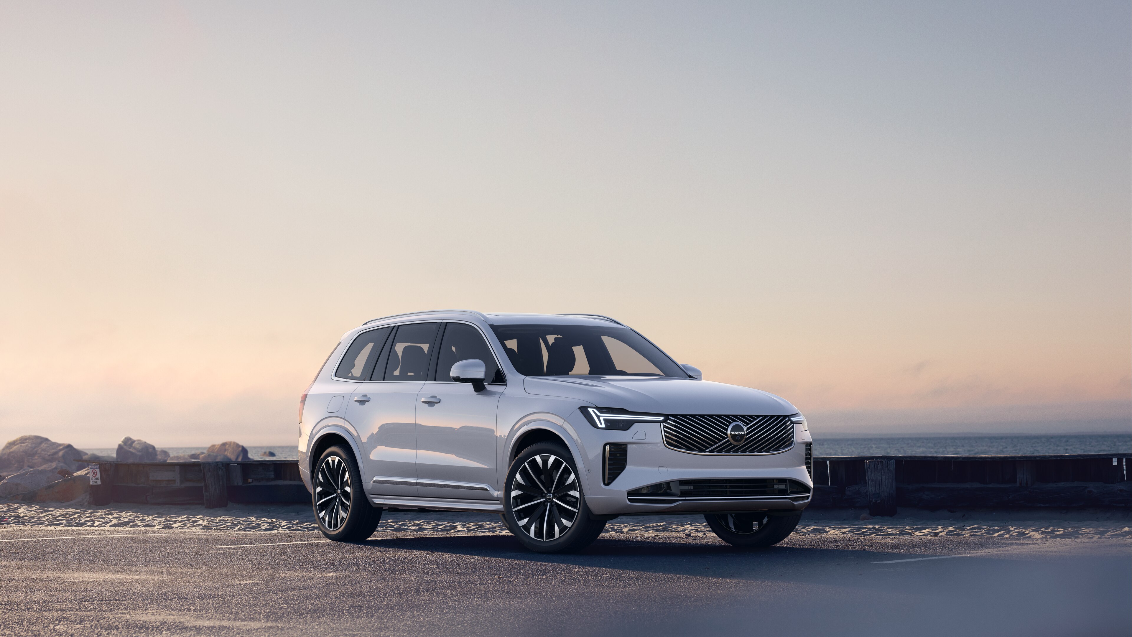 Una Volvo vista di tre quarti su una strada costiera, che mostra la parte anteriore e laterale su uno sfondo sereno dell'oceano.