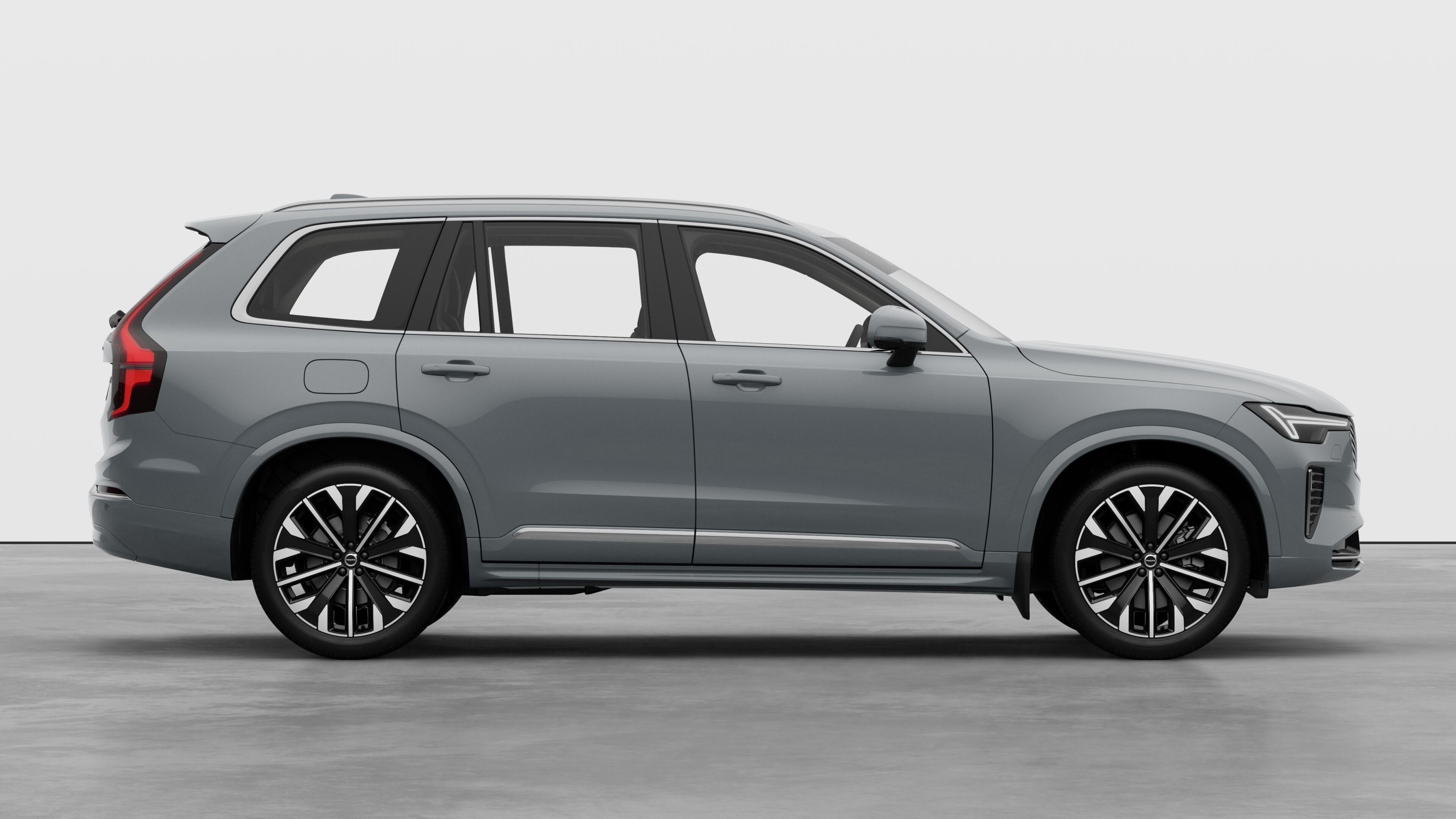 Volvo-bilens sidevisning på vanlig studiobakgrunn som viser lukkede dører og synlig hjuldesign.