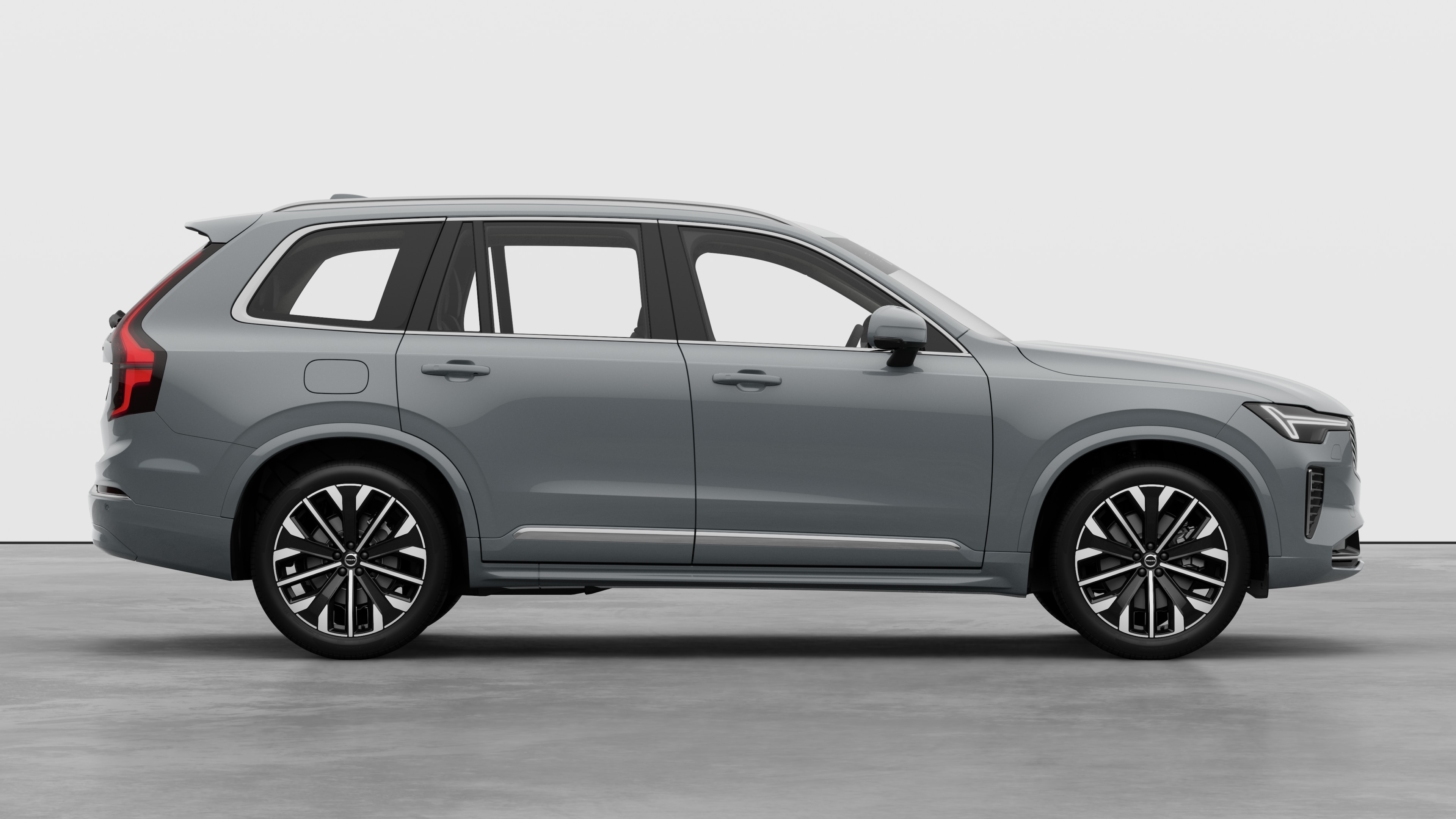 Volvo automašīnas sānskats uz vienkārša studijas fona, kurā redzamas aizvērtas durvis un redzams riteņu dizains.
