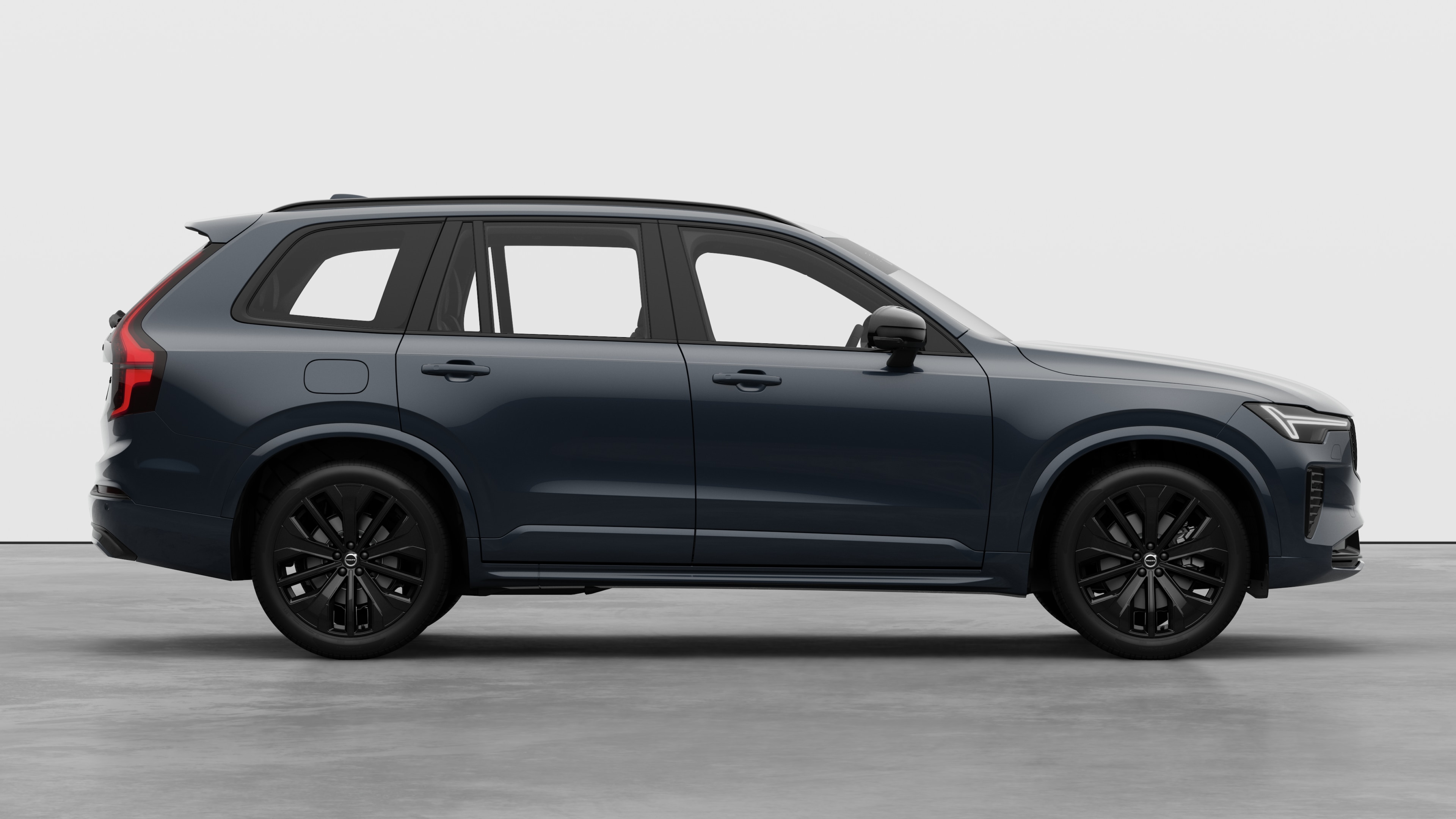 Seitenansicht eines Volvo Fahrzeugs auf einem schlichten Studiohintergrund mit geschlossenen Türen und sichtbarem Raddesign.