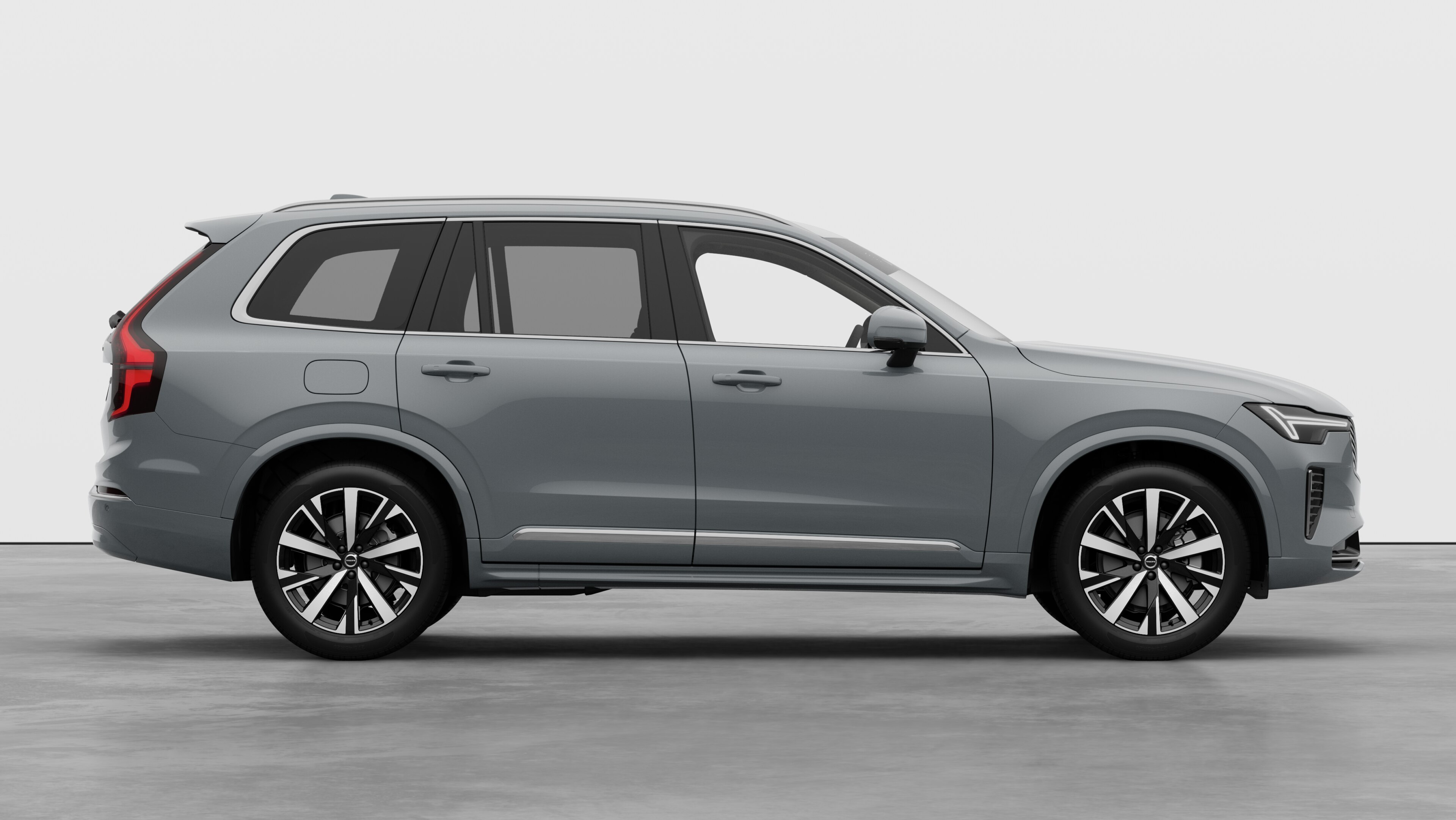 Volvo avtomobil yan görünüşü qapalı qapıları və görünən təkər dizaynını nümayiş etdirən sadə studiya fonunda.