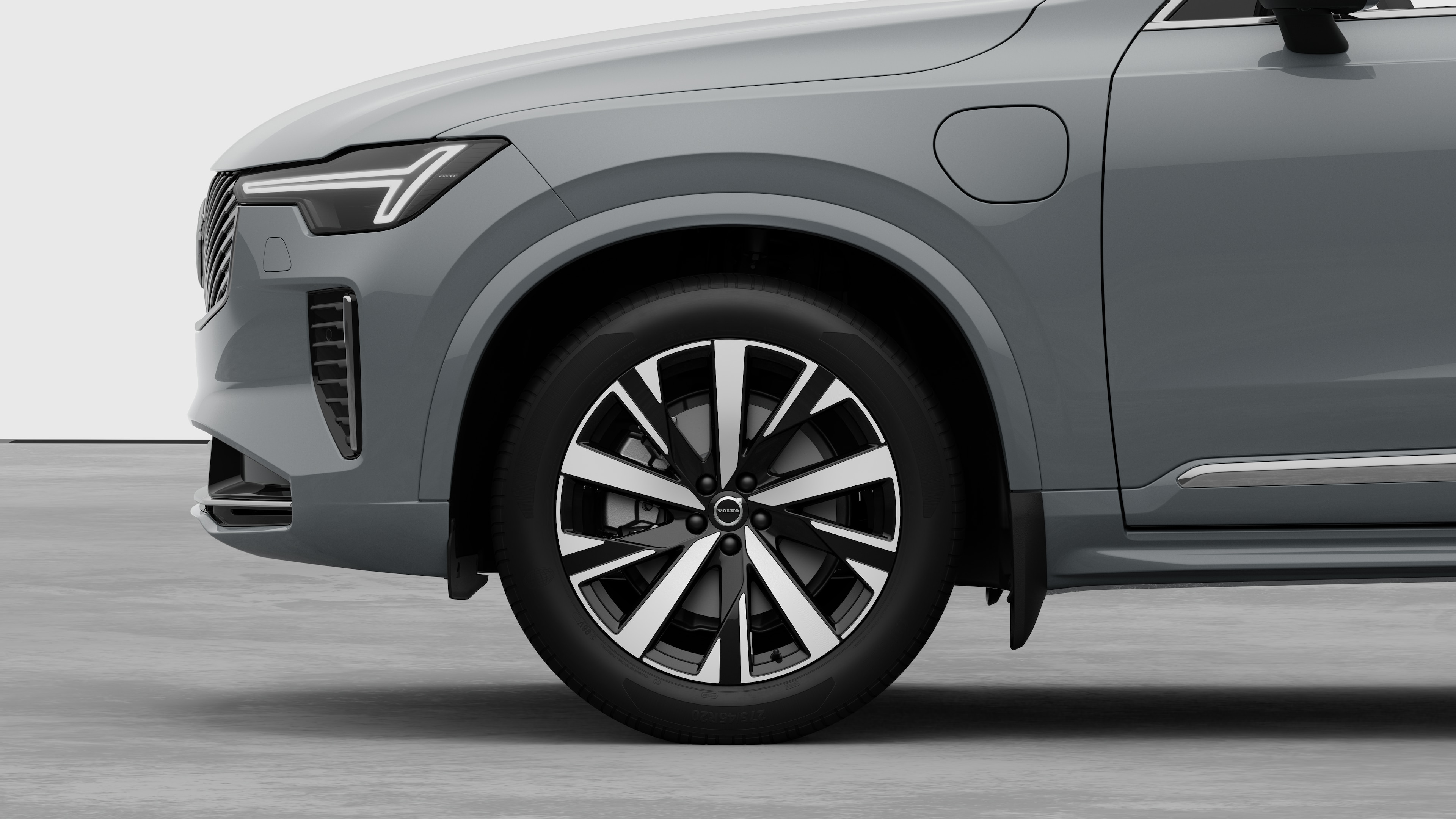 Volvo-auton sivunäkymä ulkopuolelta keskittyen etupyörään ja lokasuojaan studiotaustaa vasten.