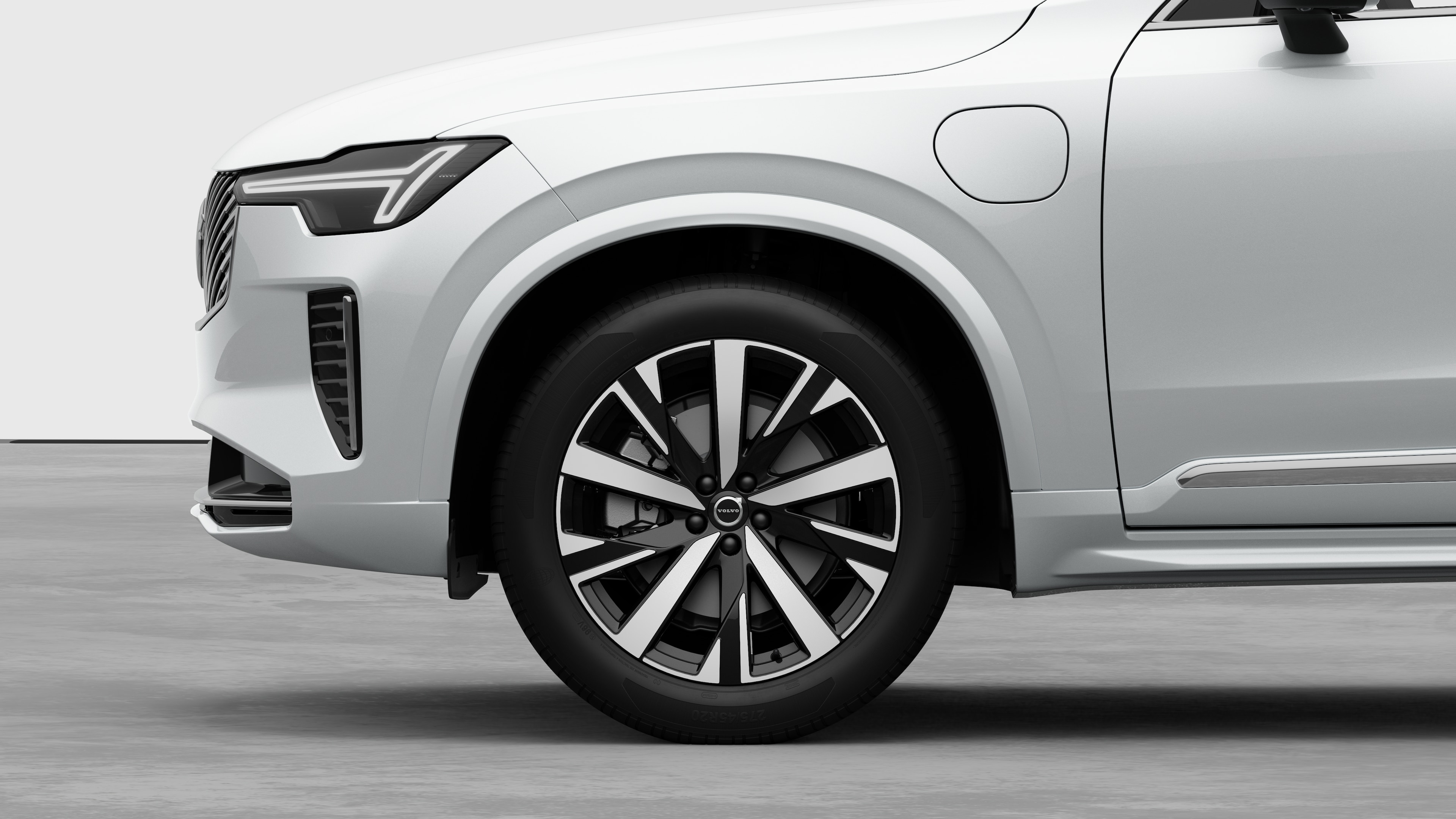 Vista lateral exterior do automóvel Volvo centrada na roda dianteira e no guarda-lamas, contra um fundo de estúdio simples.