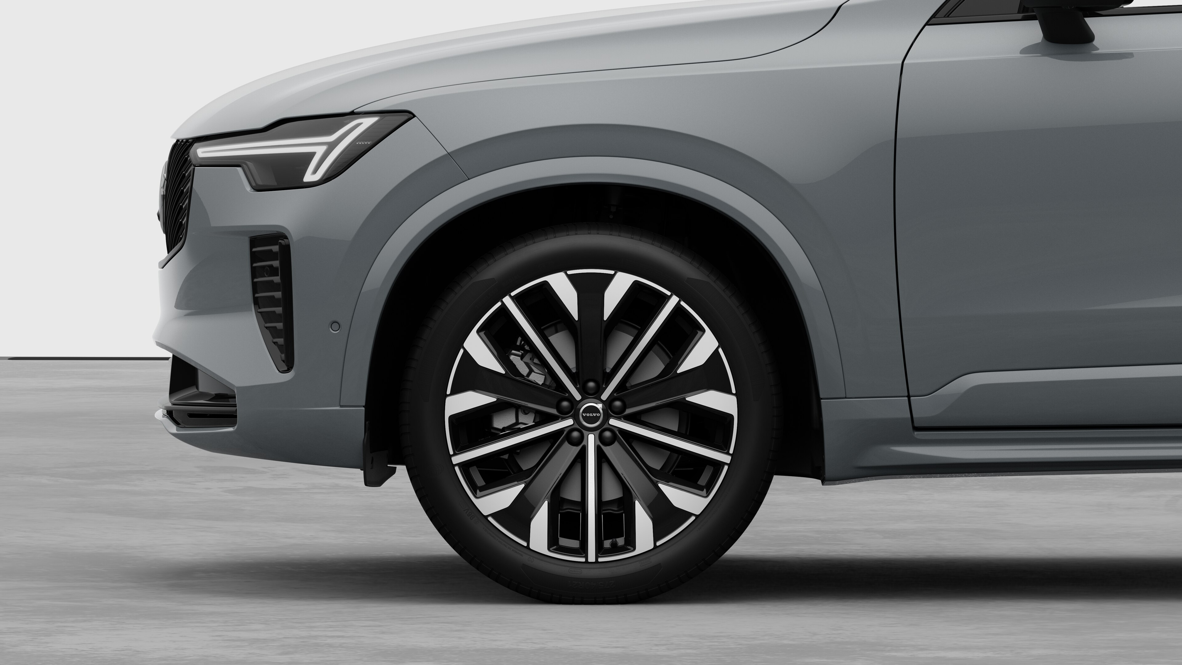 Volvo car exterior side view focusing on the front wheel and fender, set against a plain studio background.