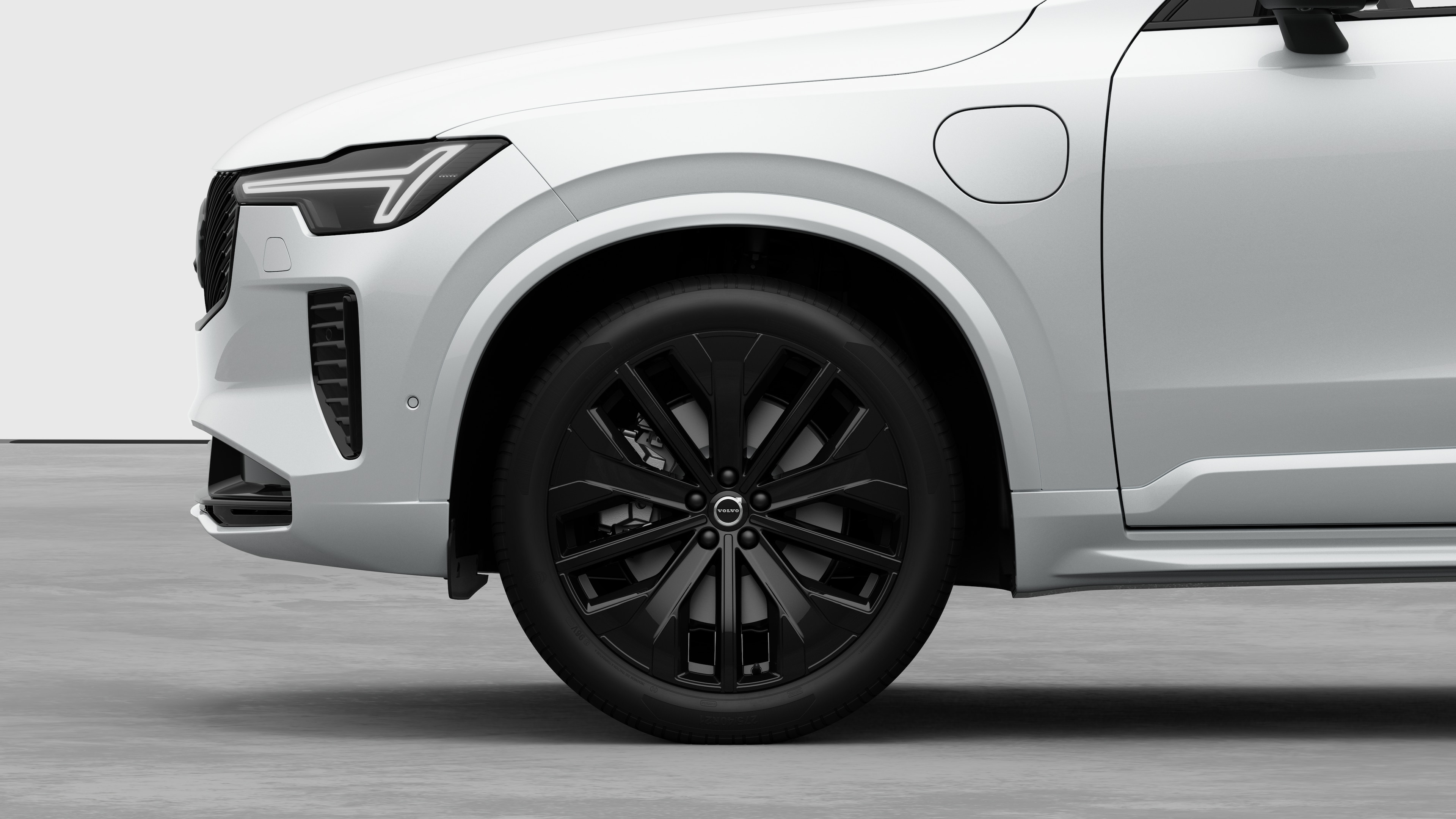 Widok boczny z zewnątrz samochodu Volvo, skupiający się na przednim kole i błotniku, na tle zwykłego studia