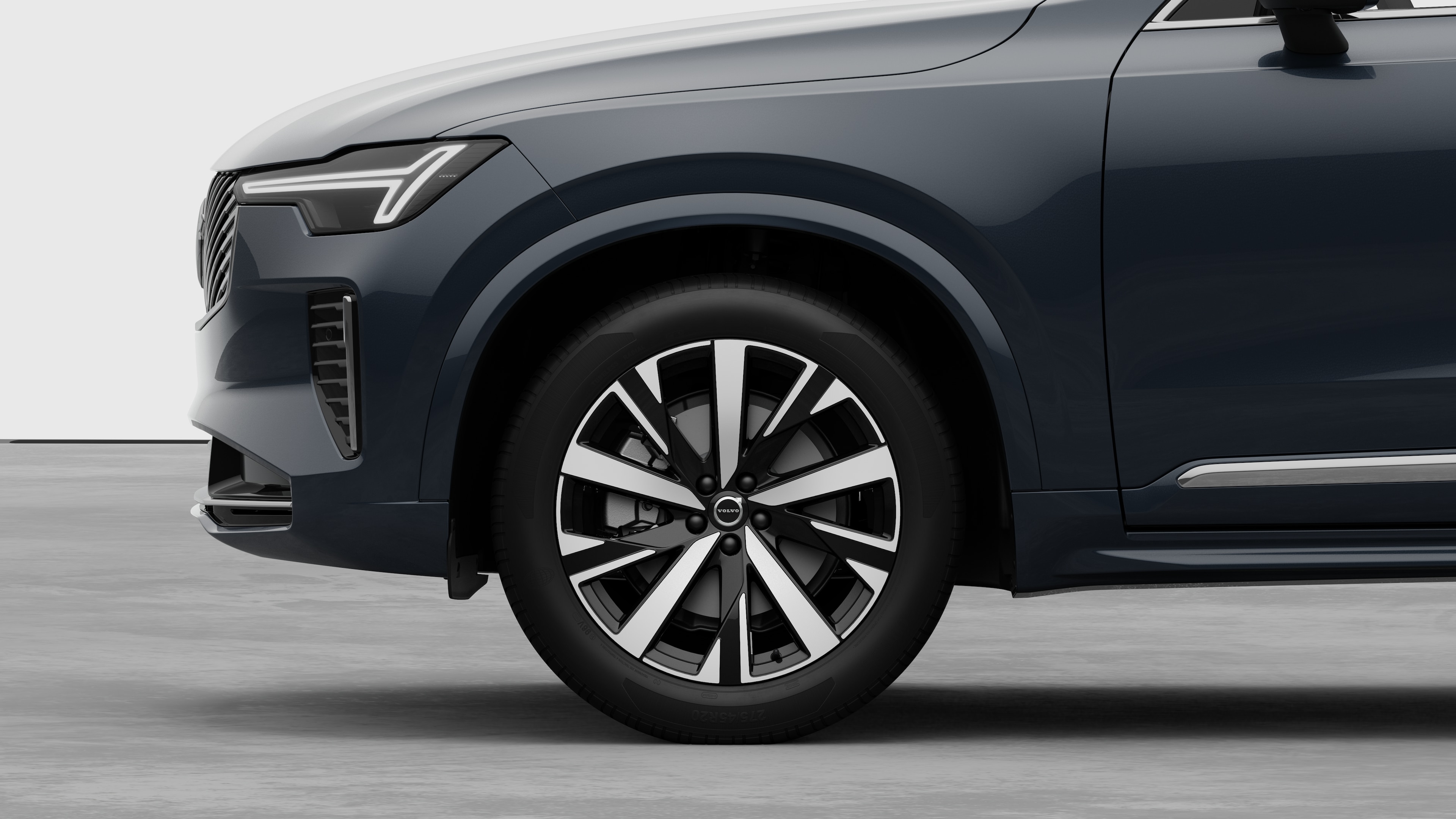 Екстер'єр автомобіля Volvo з акцентом на передньому колесі та крилі на однотонному студійному тлі.