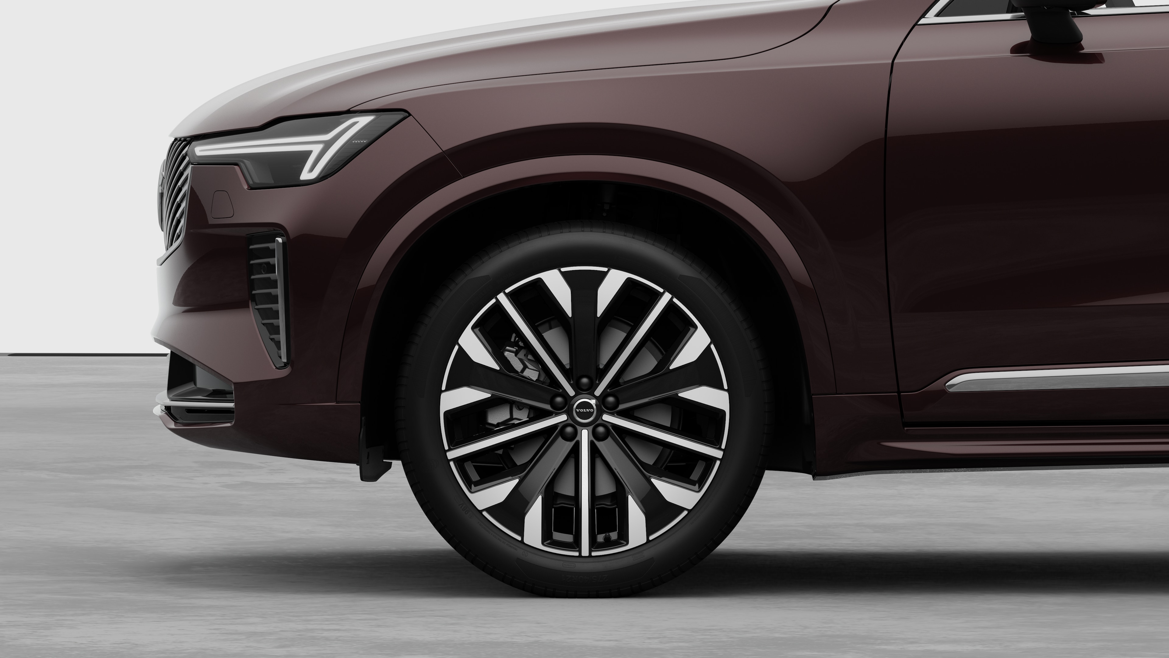 Екстер'єр автомобіля Volvo з акцентом на передньому колесі та крилі на однотонному студійному тлі.