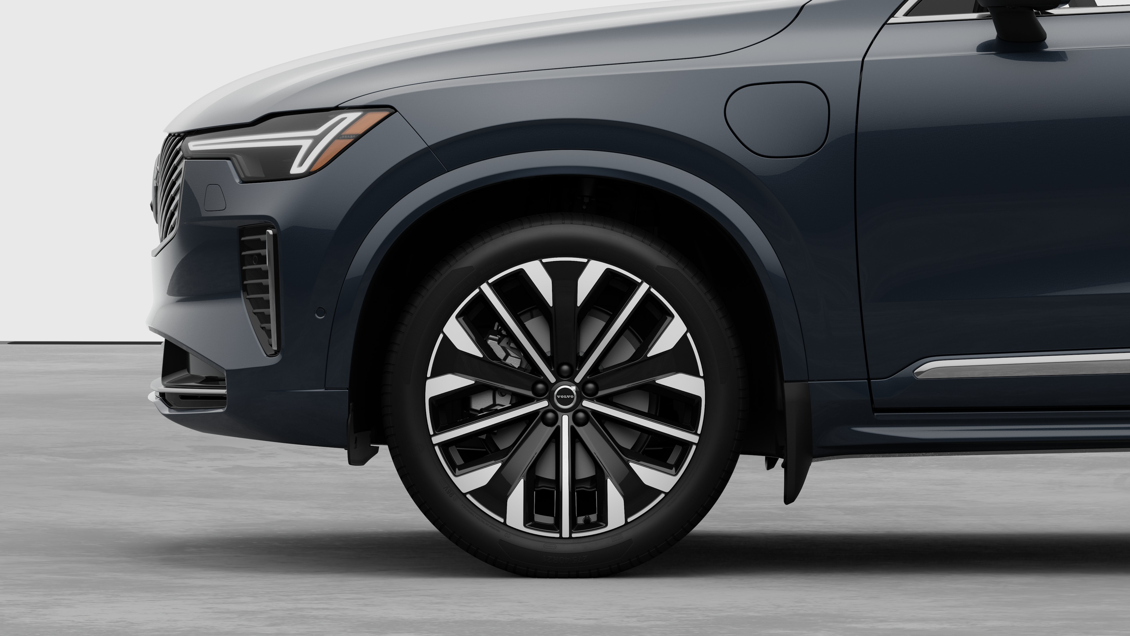 Volvo car exterior side view focusing on the front wheel and fender, set against a plain studio background.