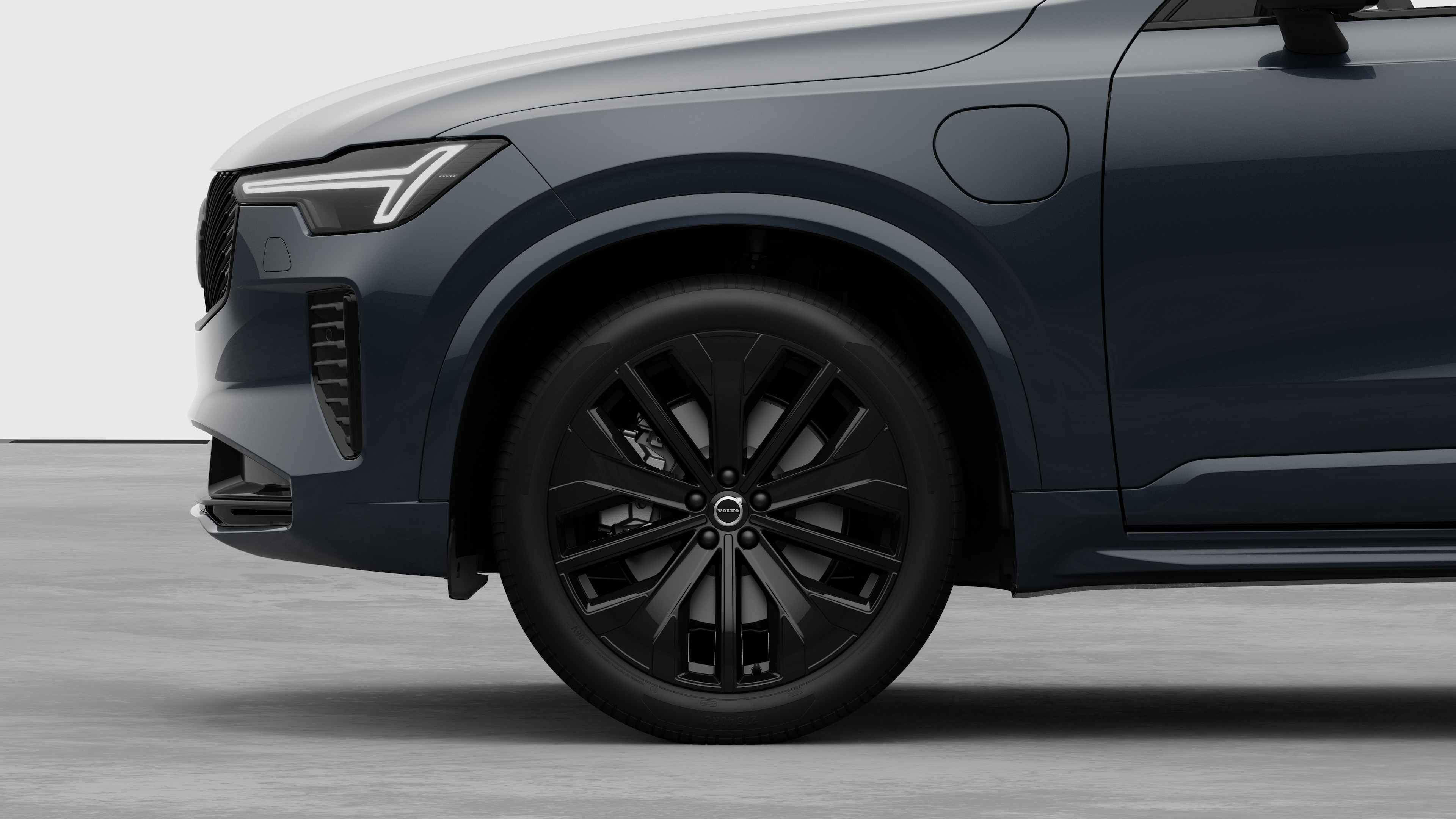 Seitenansicht eines Volvo Fahrzeugs mit Fokus auf Vorderrad und Kotflügel vor einem schlichten Studiohintergrund.