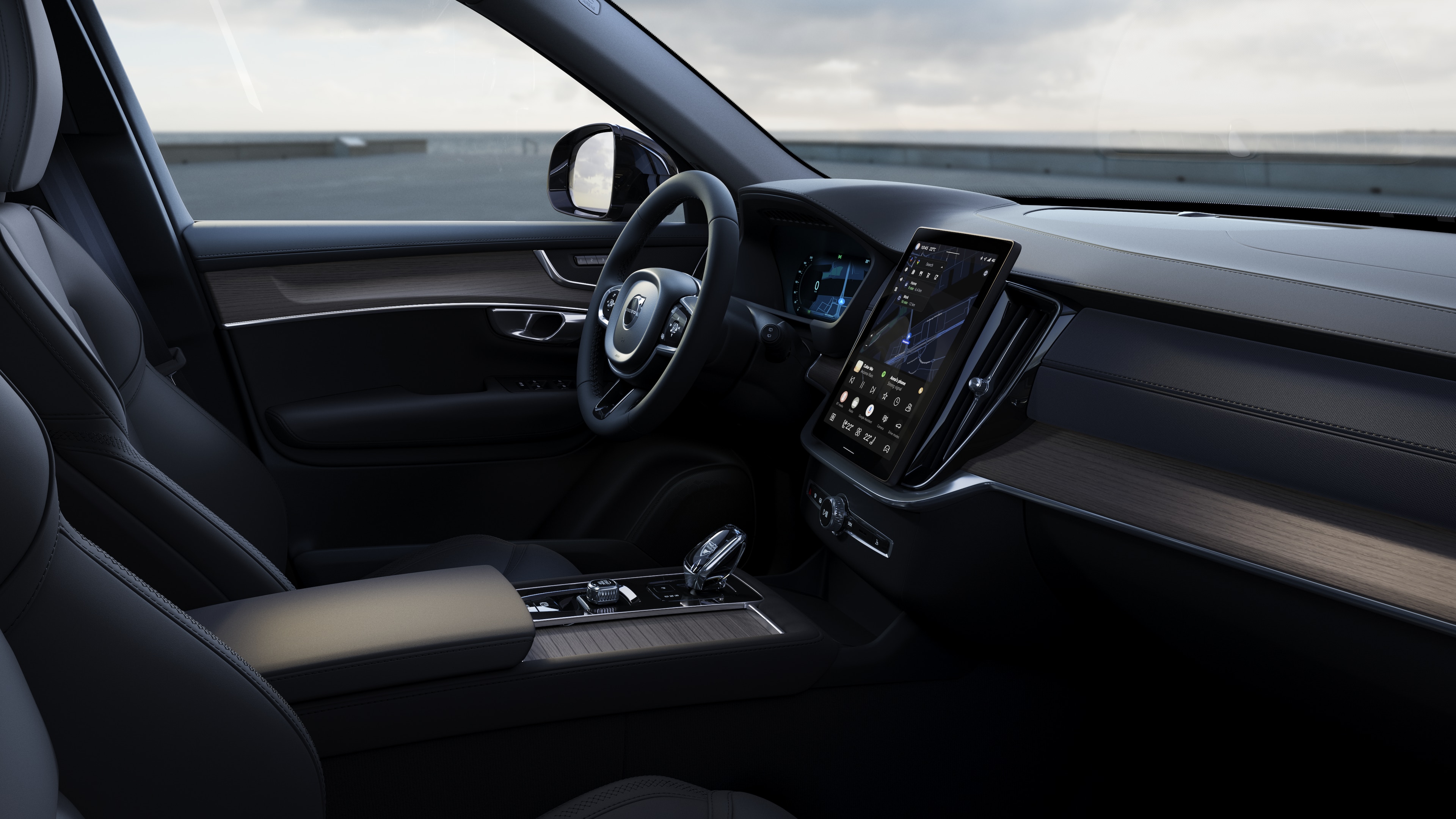 Interior del vehículo Volvo que muestra el salpicadero, el volante y la consola central con pantalla digital en un fondo de carretera abierta.