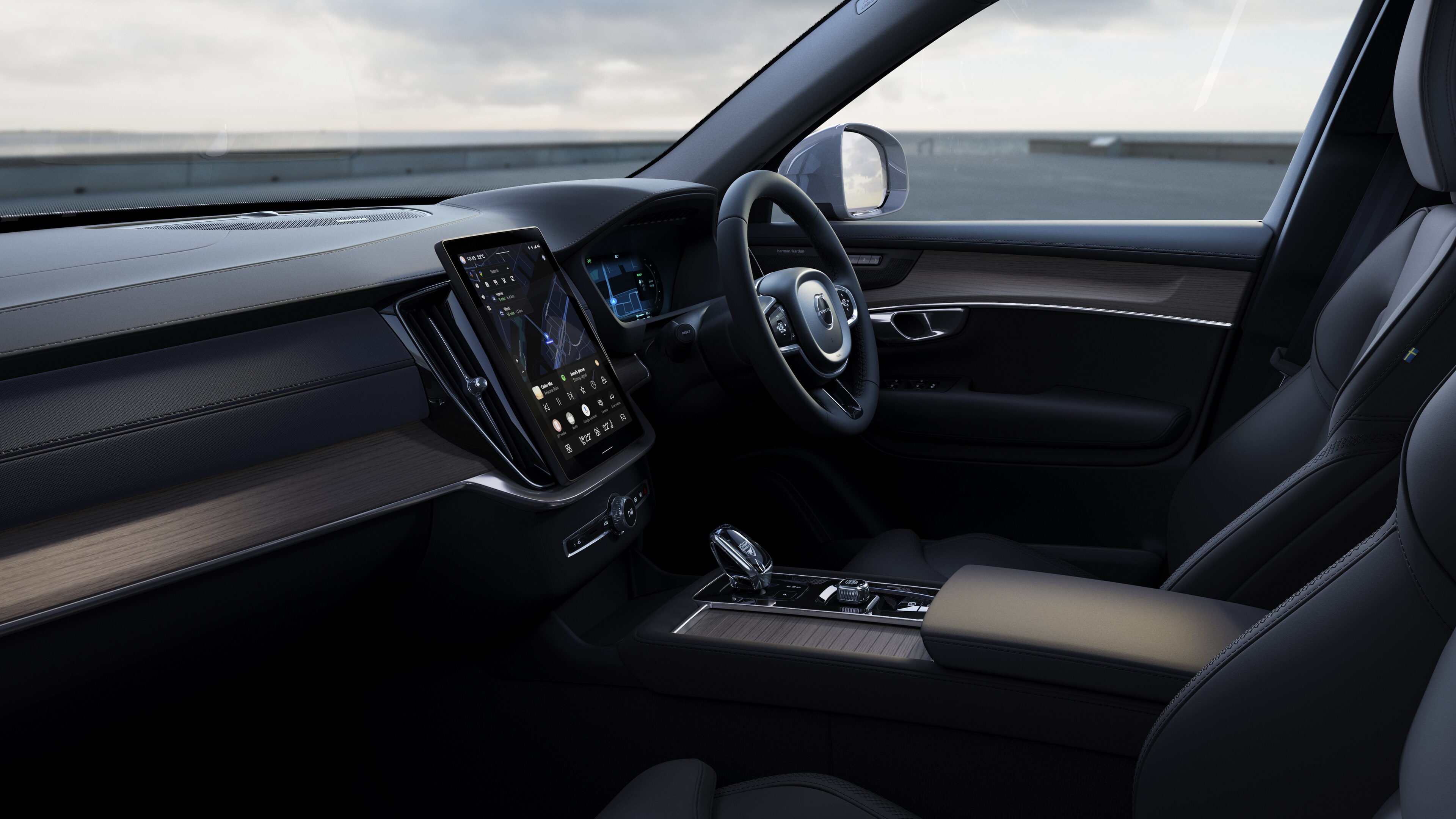Volvo car interior showing dashboard, steering wheel, and center console with digital display in an open road background.