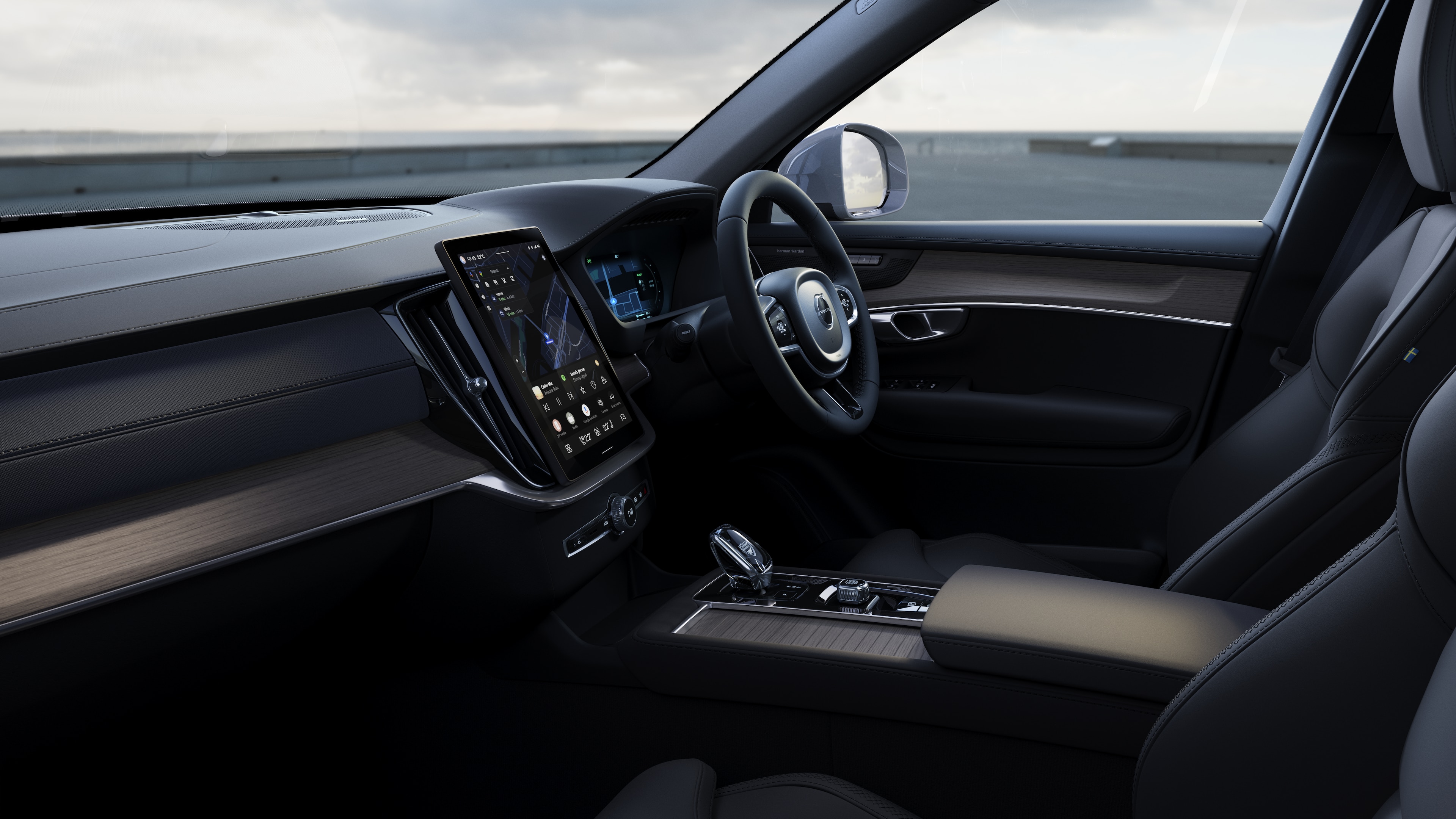 Volvo car interior showing dashboard, steering wheel, and center console with digital display in an open road background.