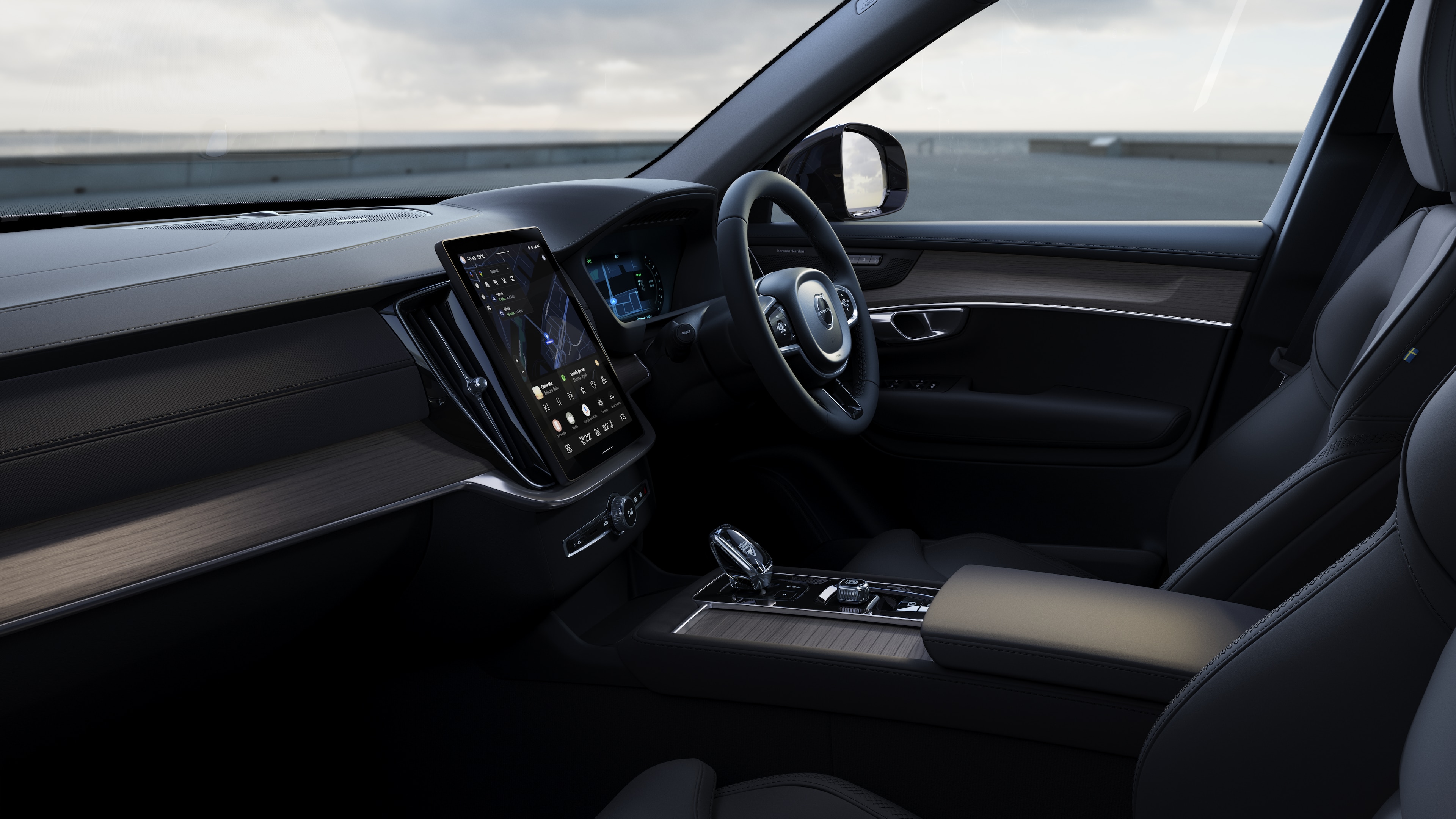 Volvo car interior showing dashboard, steering wheel, and center console with digital display in an open road background.