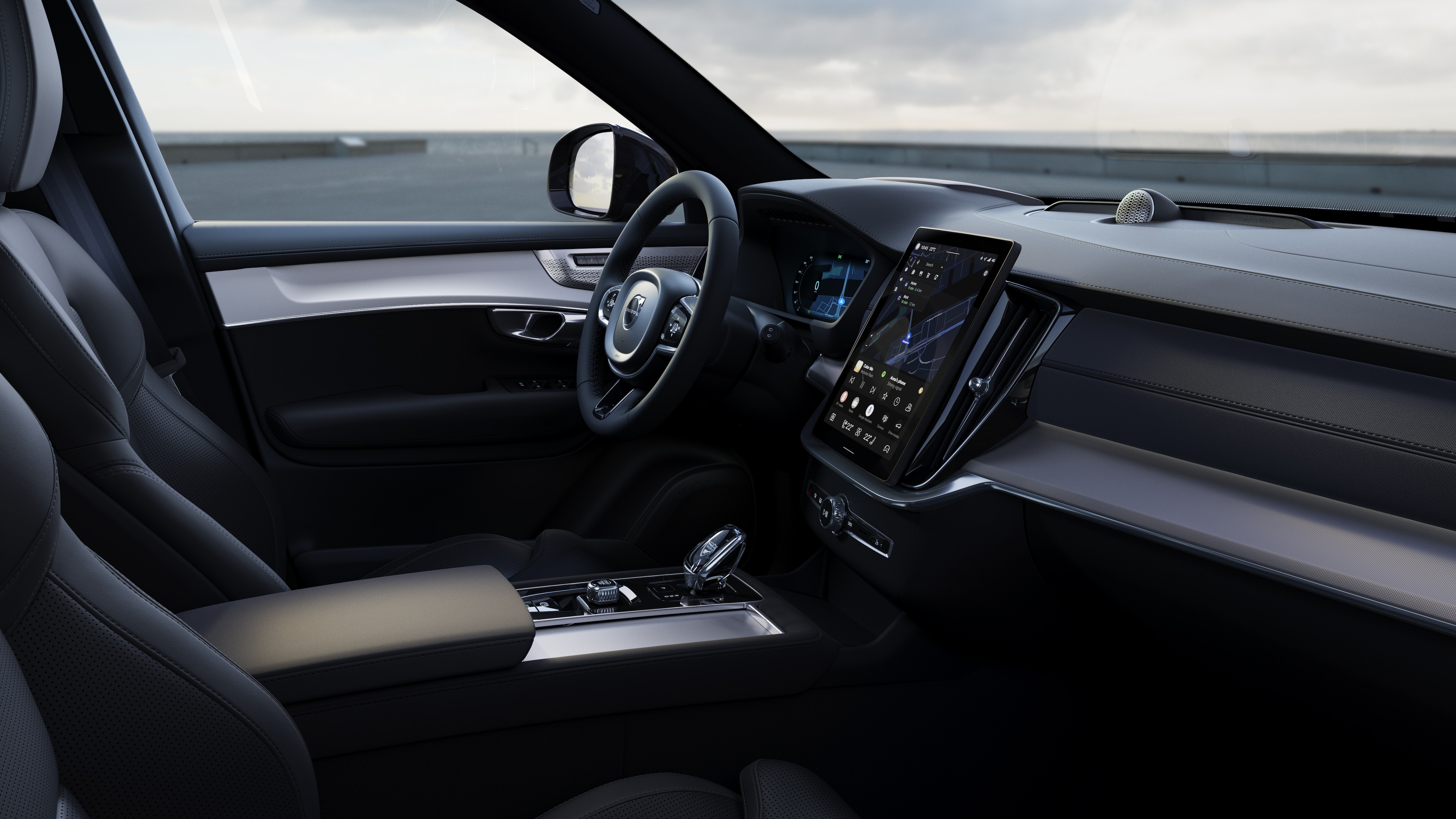Volvo-interieur met dashboard, stuur en middenconsole met digitaal display op een open wegachtergrond.