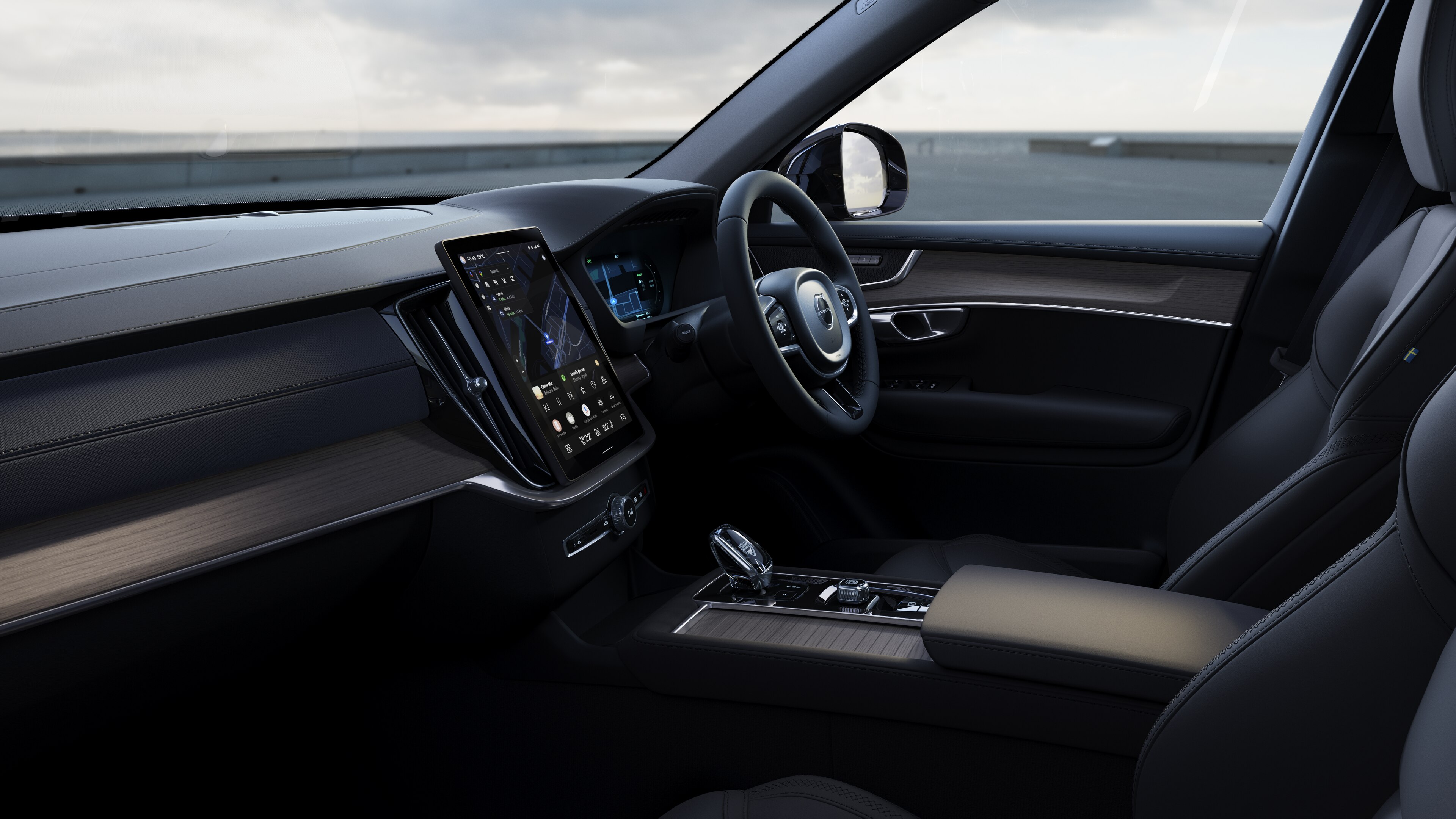 Volvo car interior showing dashboard, steering wheel, and center console with digital display in an open road background.