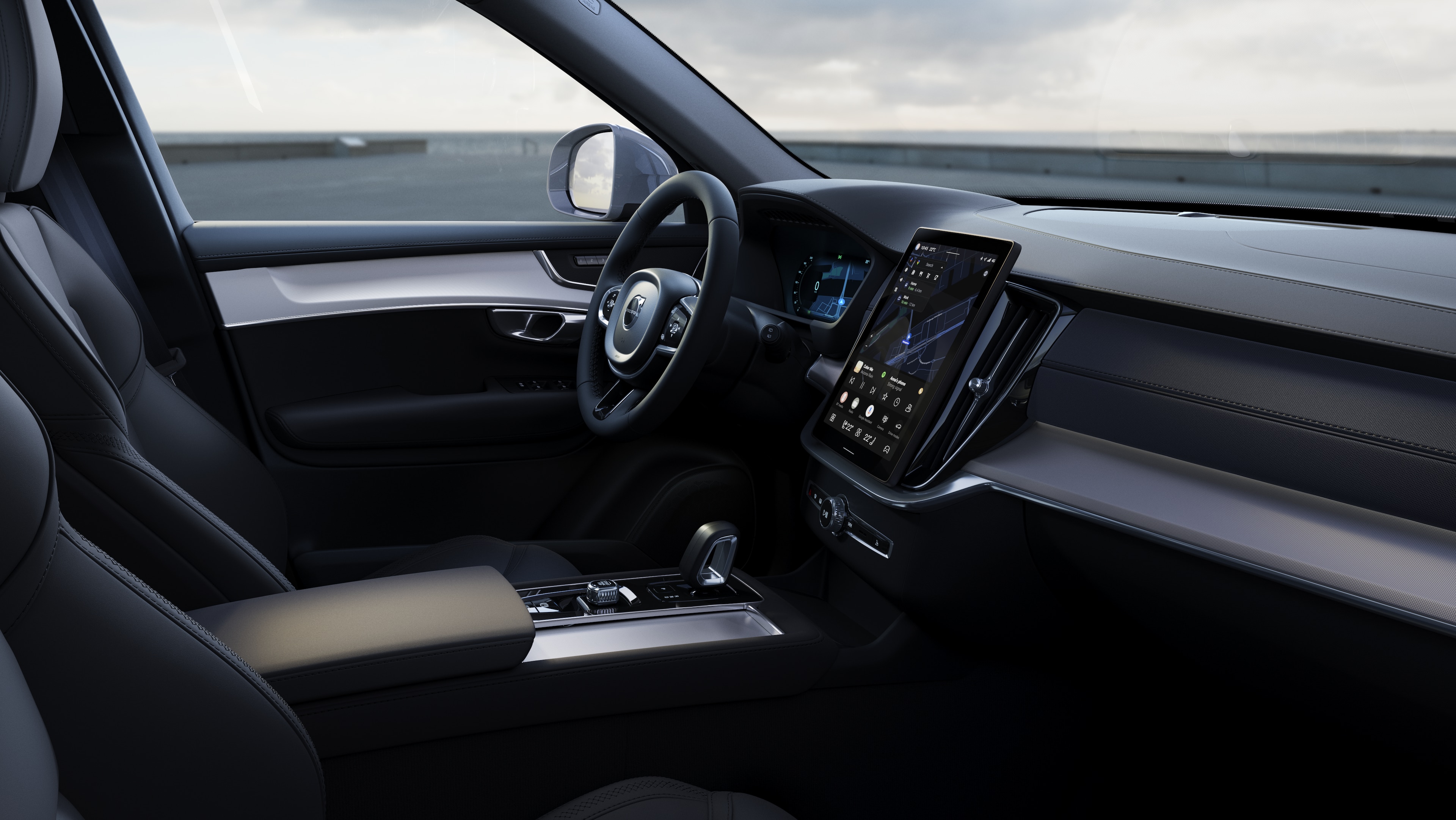 Unutrašnjost Volvo automobila koja prikazuje instrument-tablu, upravljač i centralnu konzolu sa digitalnim ekranom u otvorenom pozadini na cesti.