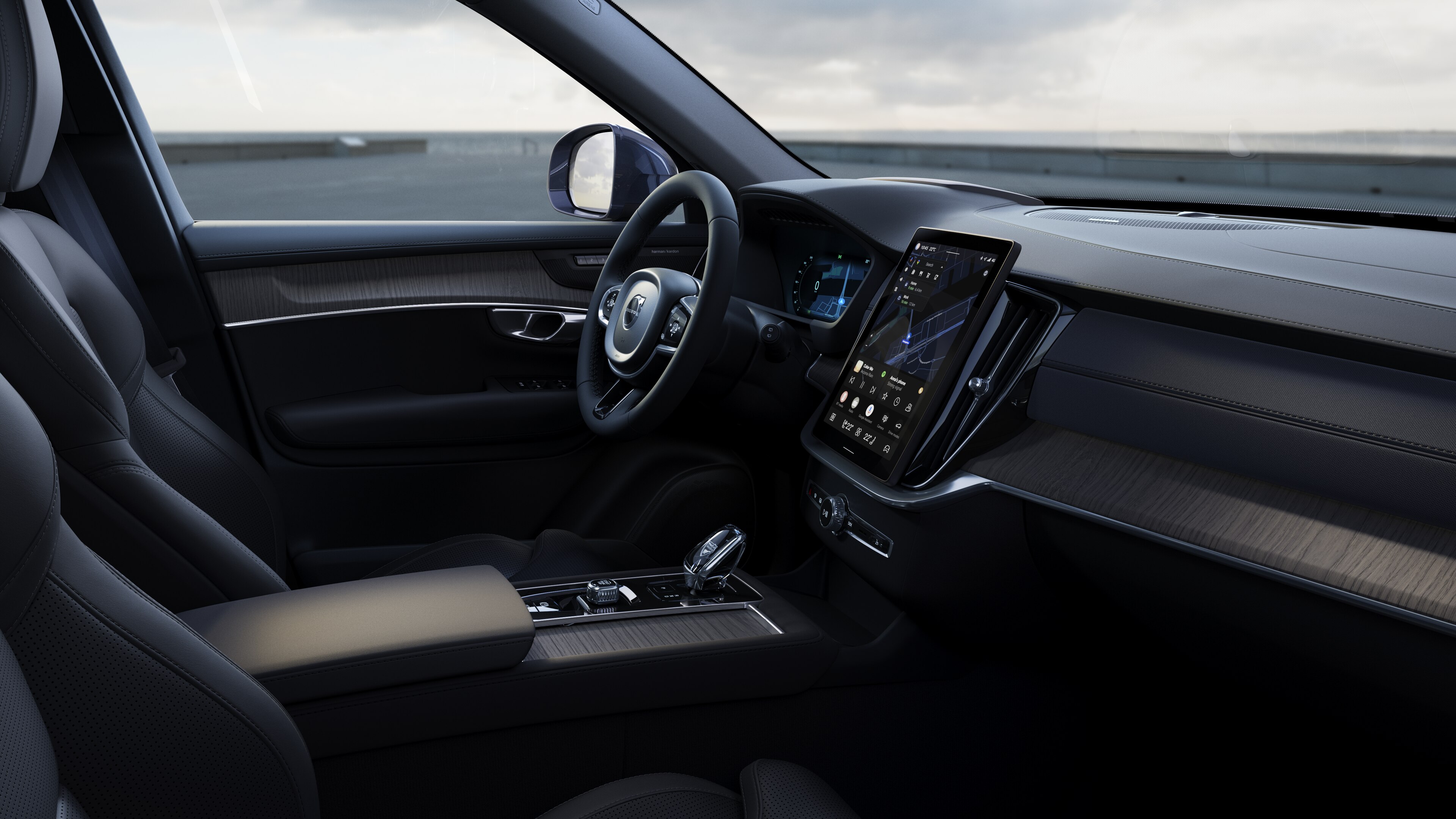 Volvo car interior showing dashboard, steering wheel, and center console with digital display in an open road background.