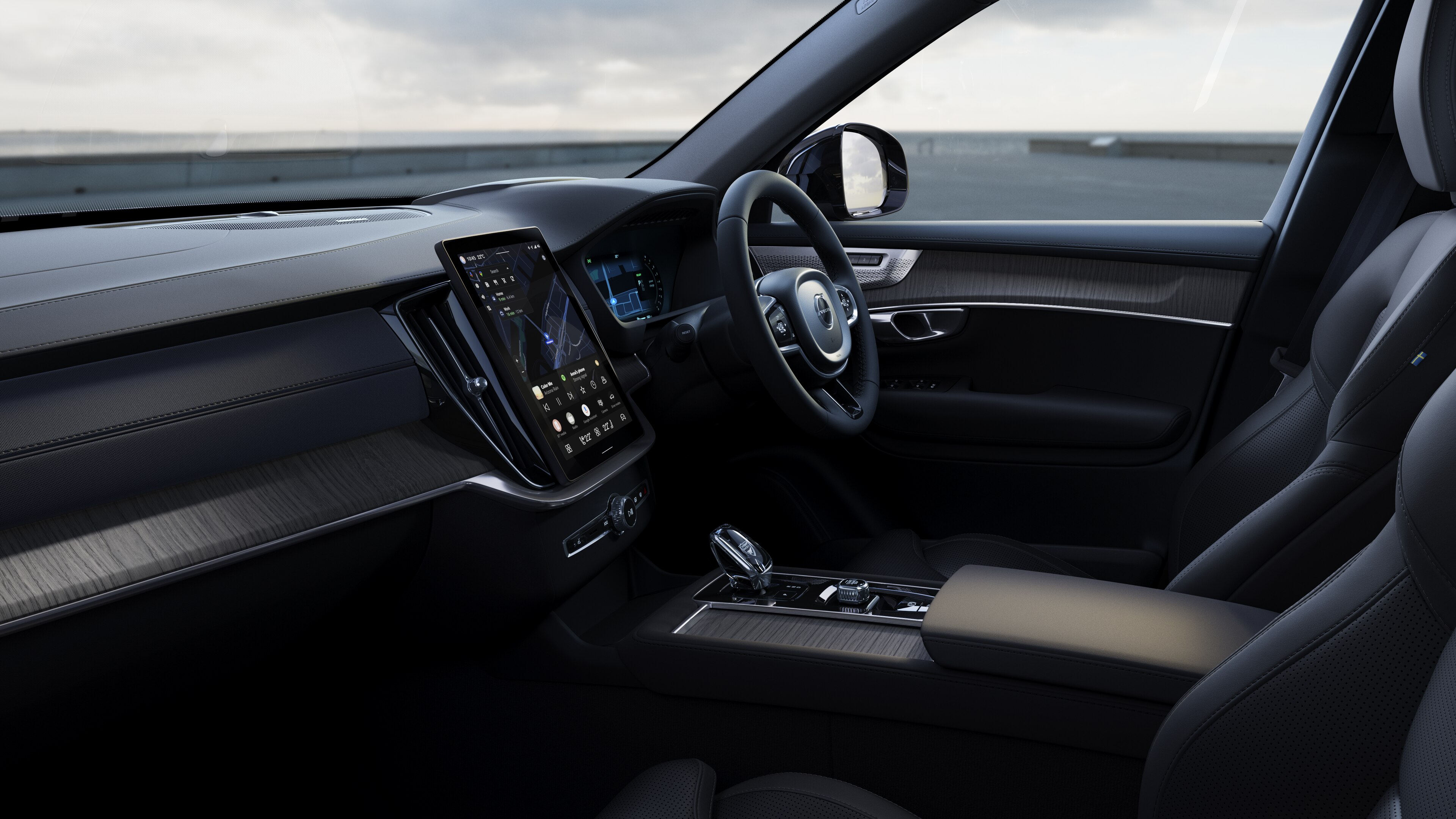 Volvo car interior showing dashboard, steering wheel, and center console with digital display in an open road background.