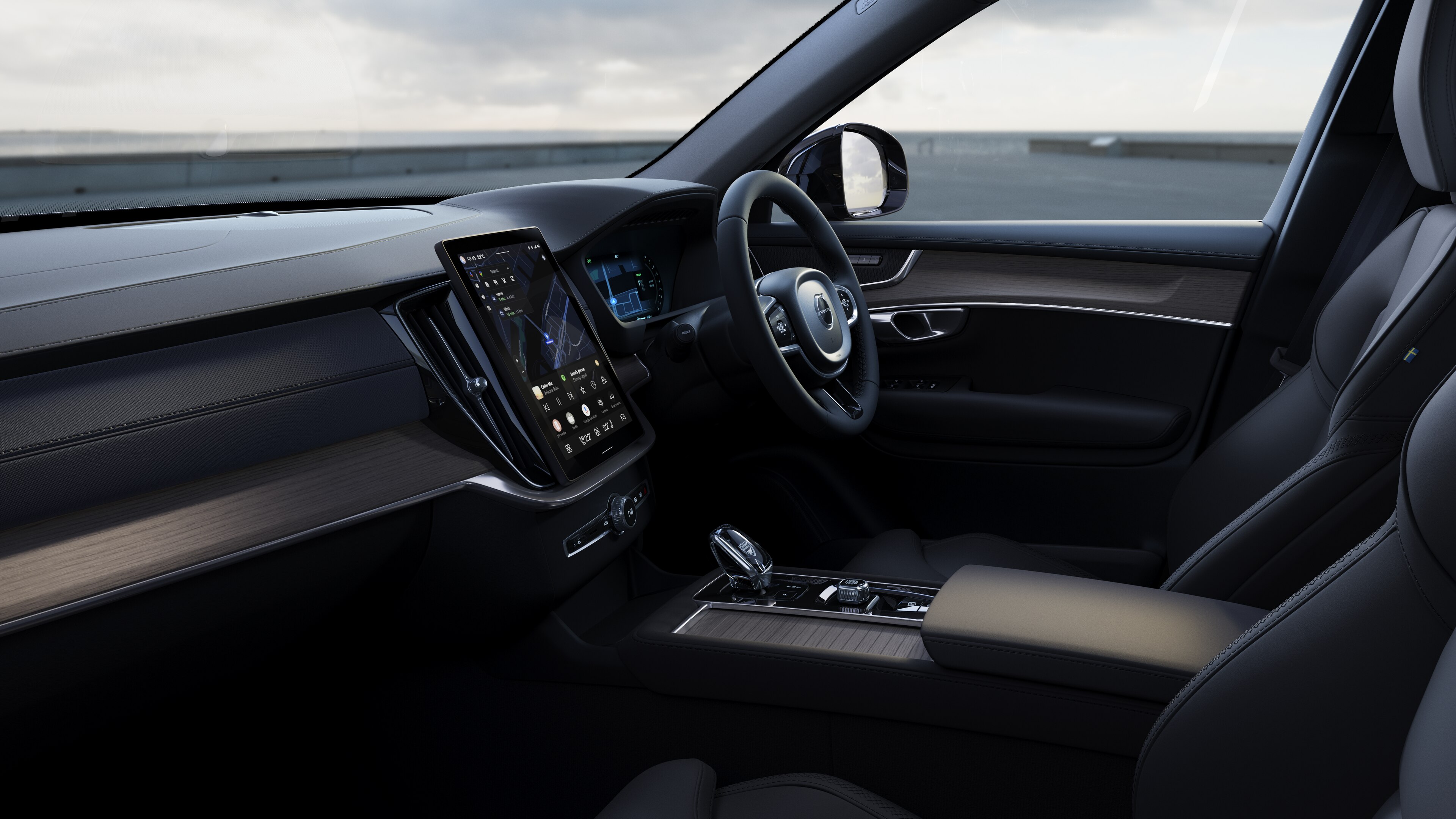 Volvo car interior showing dashboard, steering wheel, and center console with digital display in an open road background.