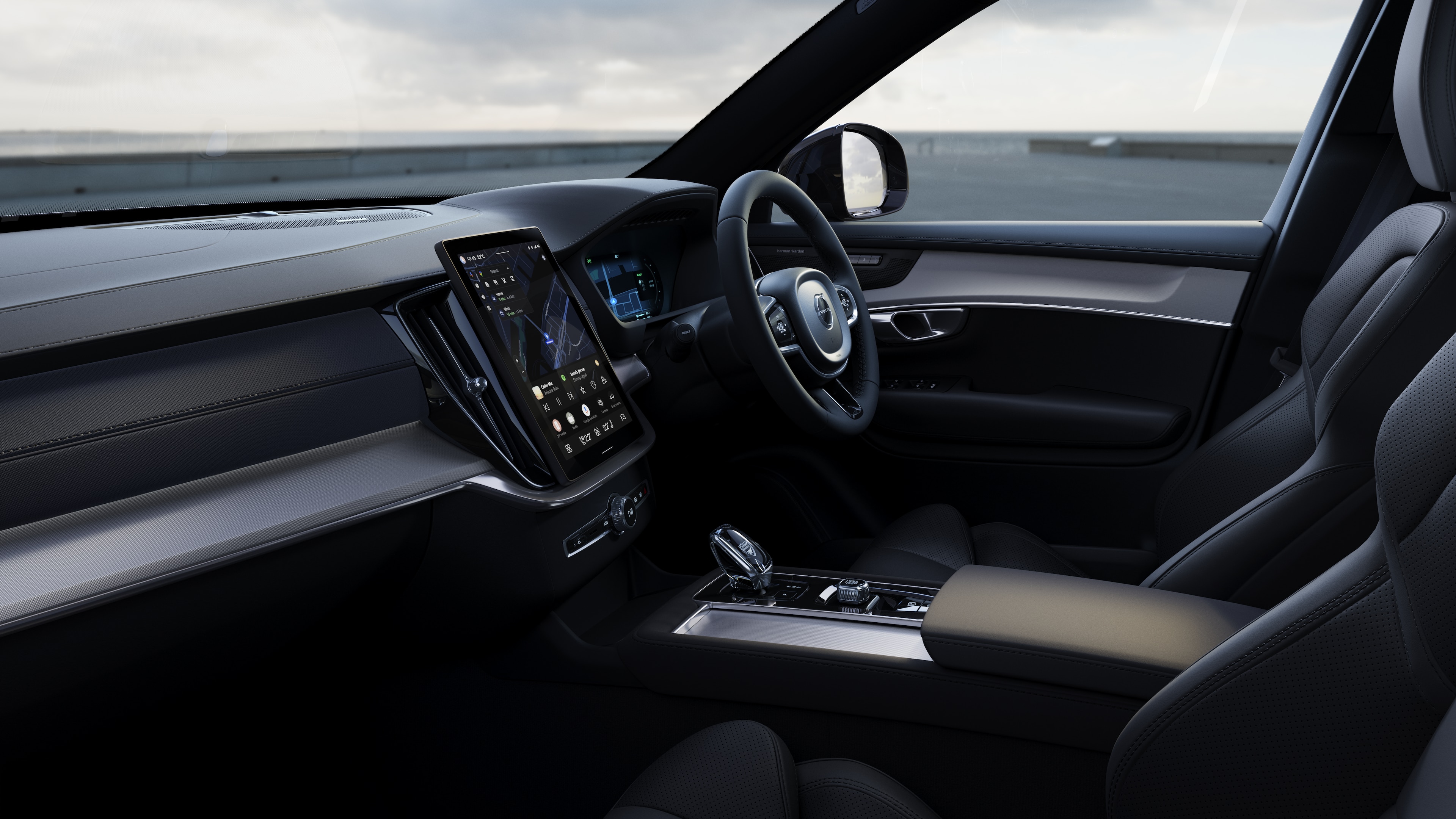 Volvo car interior showing dashboard, steering wheel, and center console with digital display in an open road background.
