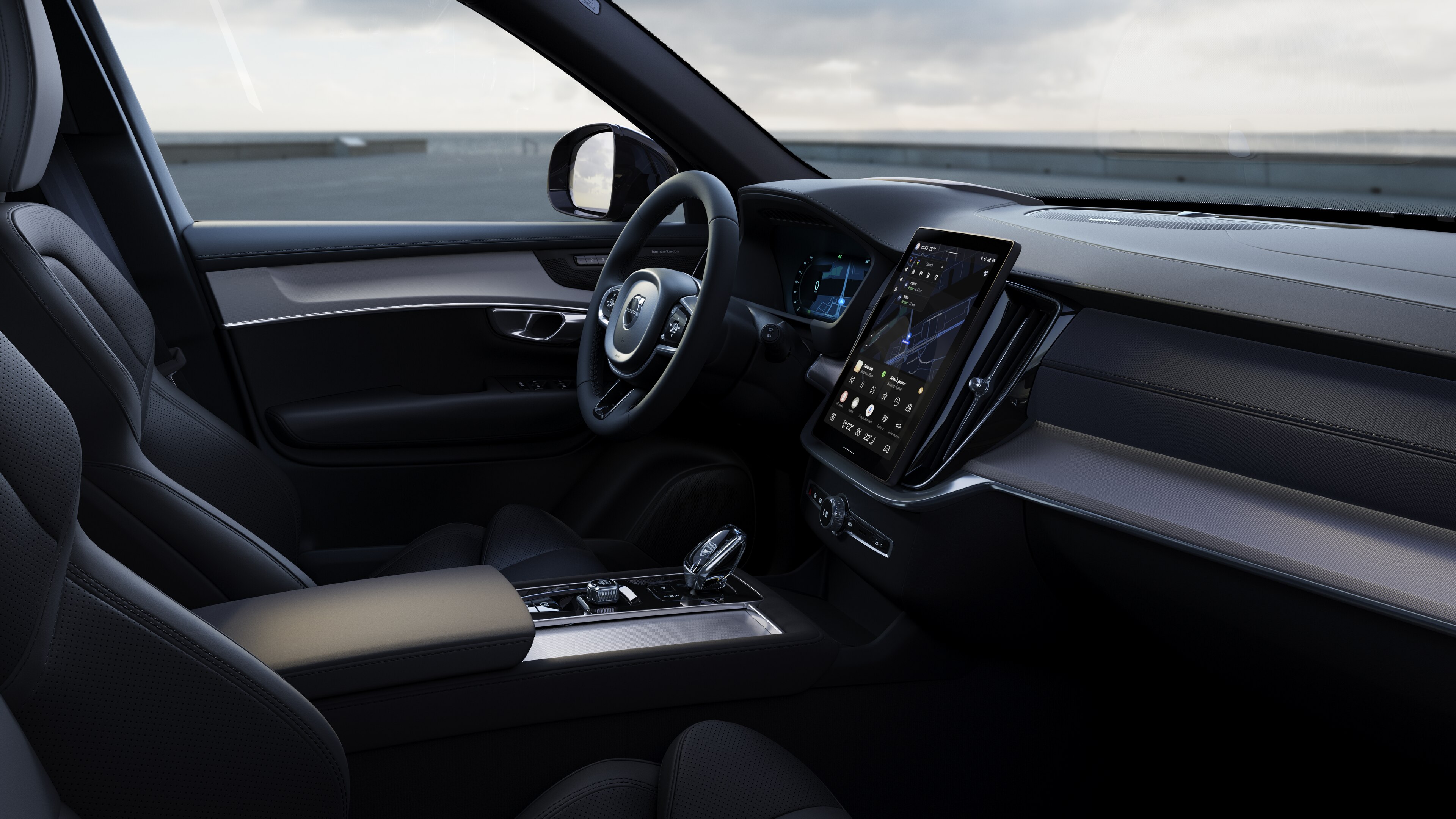 Het interieur van een Volvo met dashboard, stuur en middenconsole met digitaal display op een open wegachtergrond.