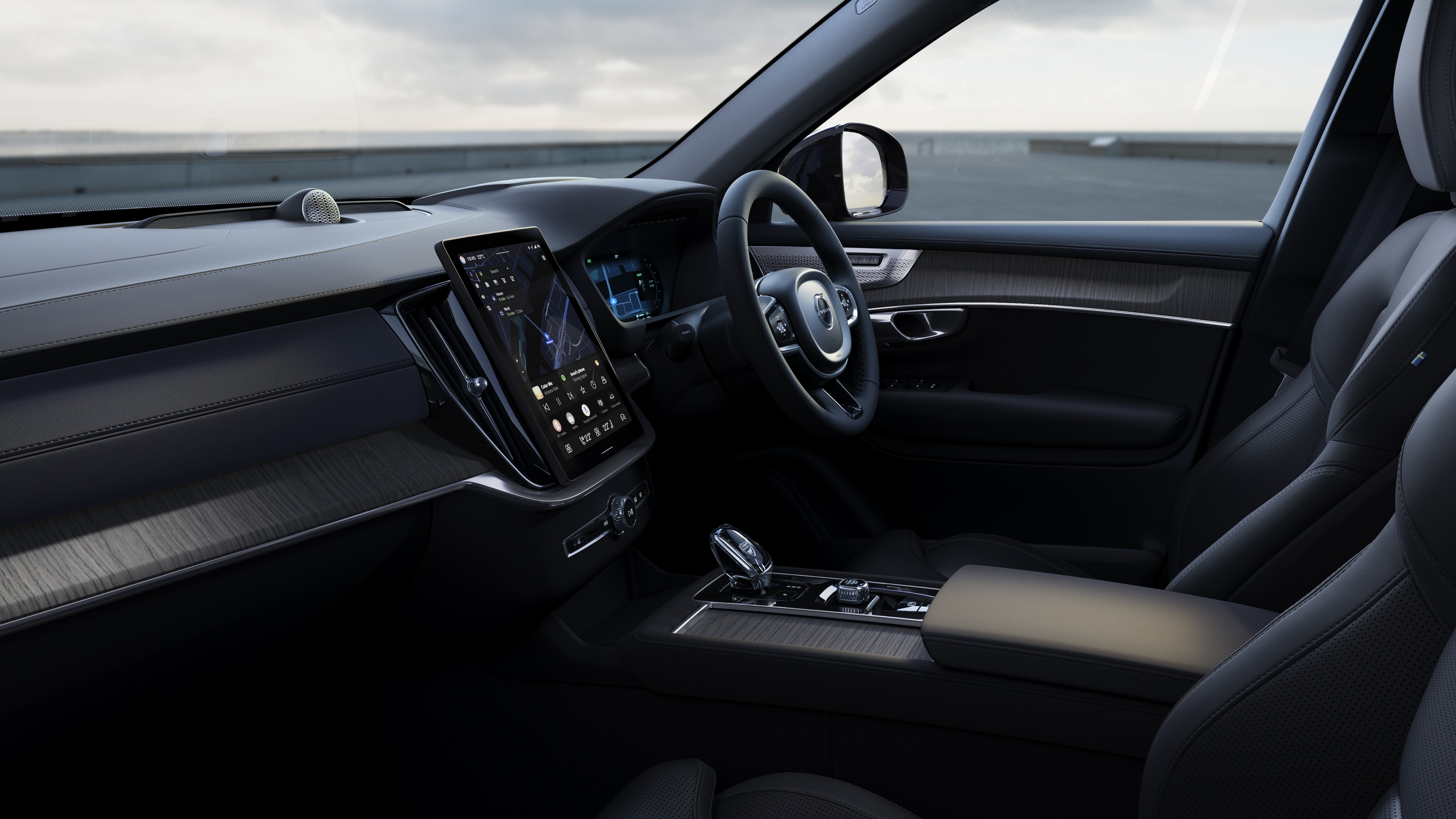 Volvo car interior showing dashboard, steering wheel, and center console with digital display in an open road background.