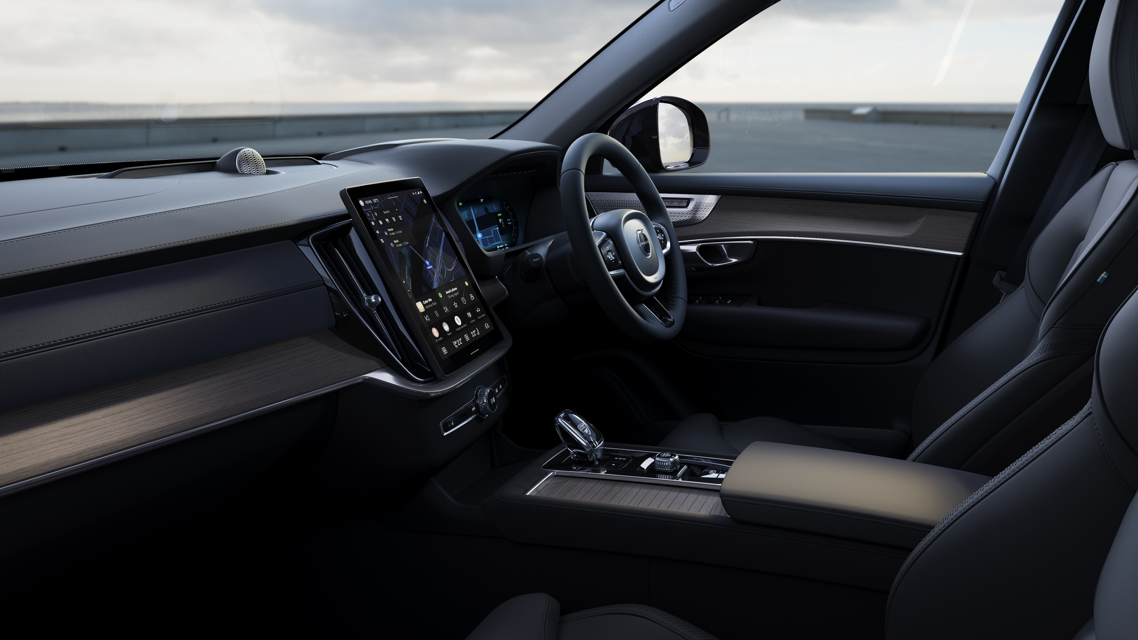 Volvo car interior showing dashboard, steering wheel, and center console with digital display in an open road background.
