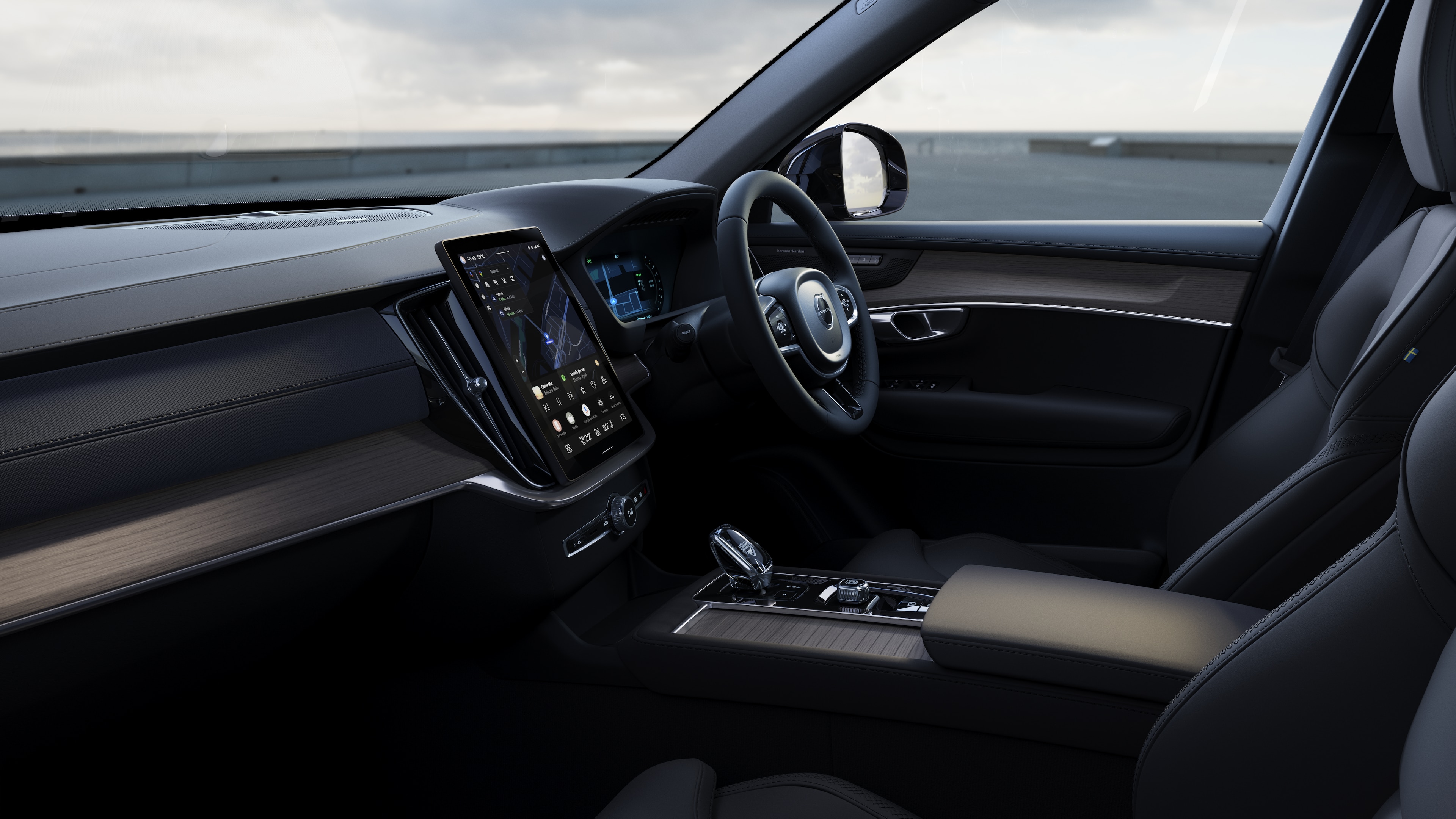 Volvo car interior showing dashboard, steering wheel, and center console with digital display in an open road background.